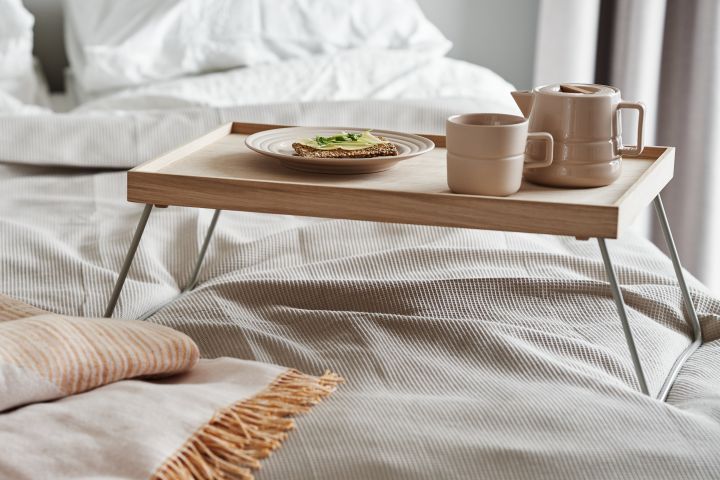 Taktiles beigefarbenes Porzellan von NJRD wird zusammen mit einem weichen Bettüberwurf aus recycelter Baumwolle zur perfekten Ergänzung für Ihr Frühstück im Bett.