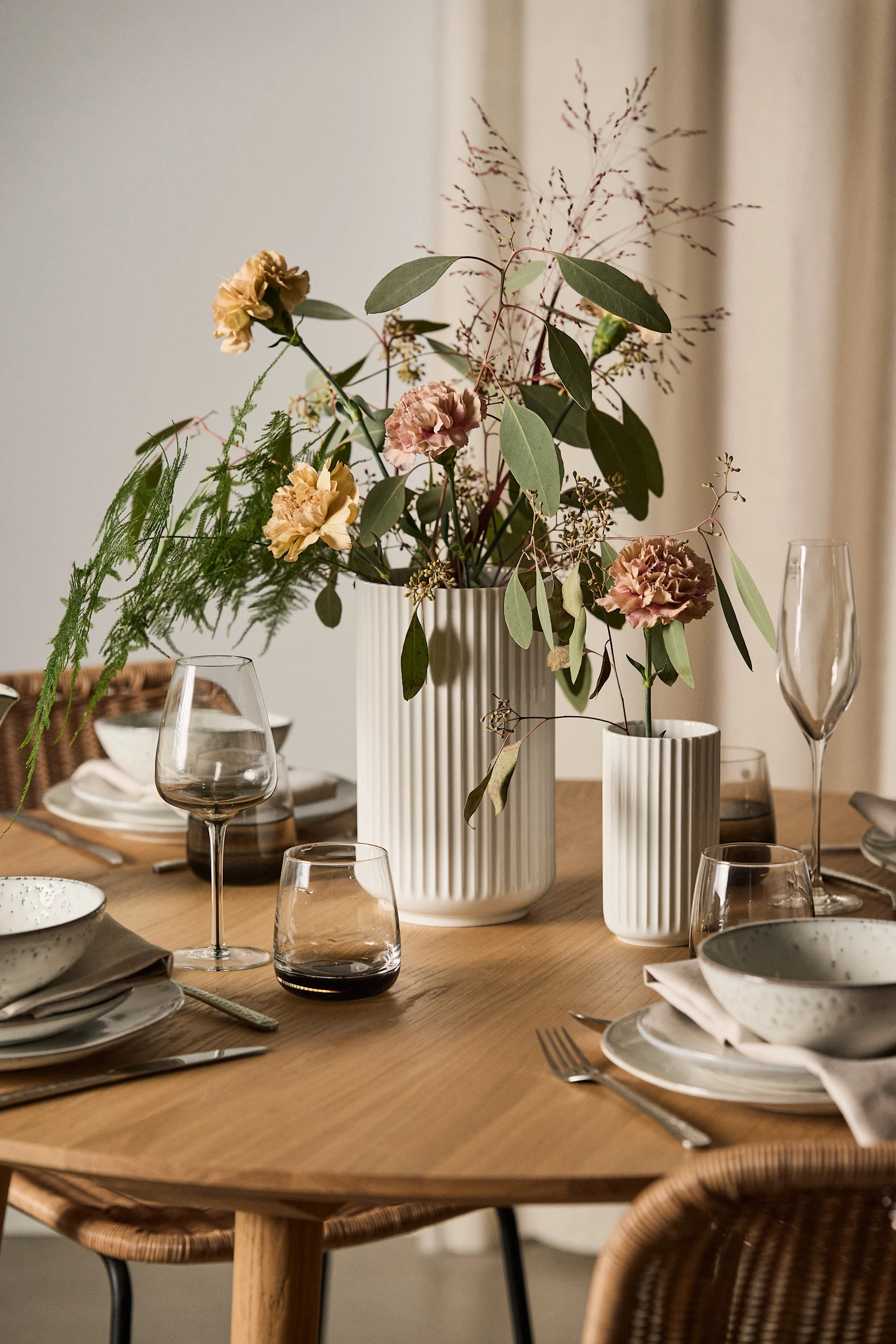 Ein nettes Geschenk zum Valentinstag sind Blumen mit einer passenden Vase. Hier stehen zwei Lyngby Vasen in Weiß mit Blumen auf einem gedeckten Tisch.