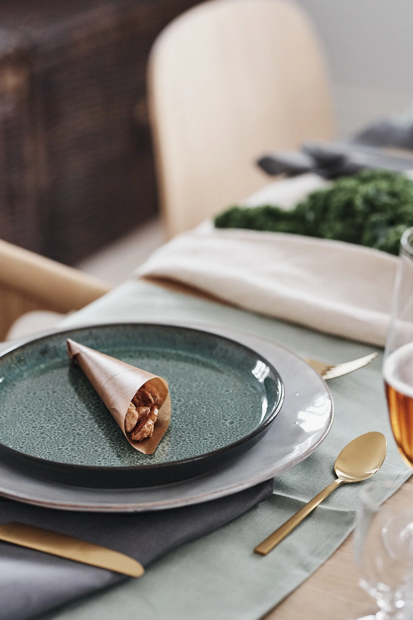 Eine Papiertüte mit kandierten Mandeln auf dem Teller wird zu einer süßen Dekoration auf dem Weihnachtstisch.