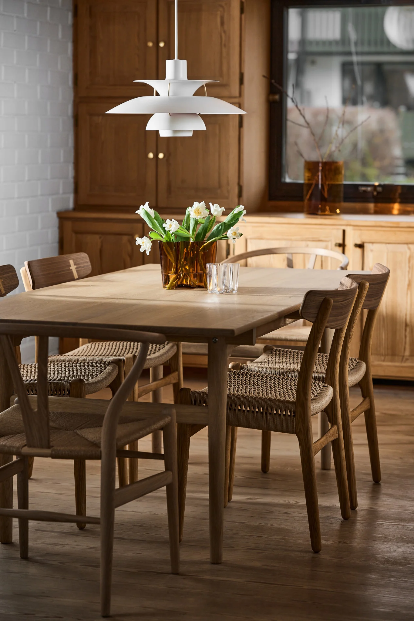 Skandinavische Lampen: Die weiße PH 5-Pendelleuchte von Louis Poulsen hängt über einem Esstisch in einem skandinavischen Esszimmer.