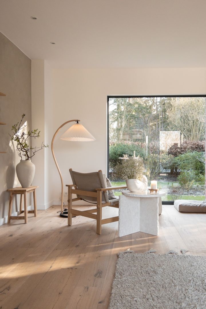 Kreieren Sie ein skandinavisches Zuhause - hier sehen Sie das Wohnzimmer von @haus_tannenkamp mit der geschwungenen Gubi-Lampe und dem weißen Mineral-Tisch von Ferm Living. 