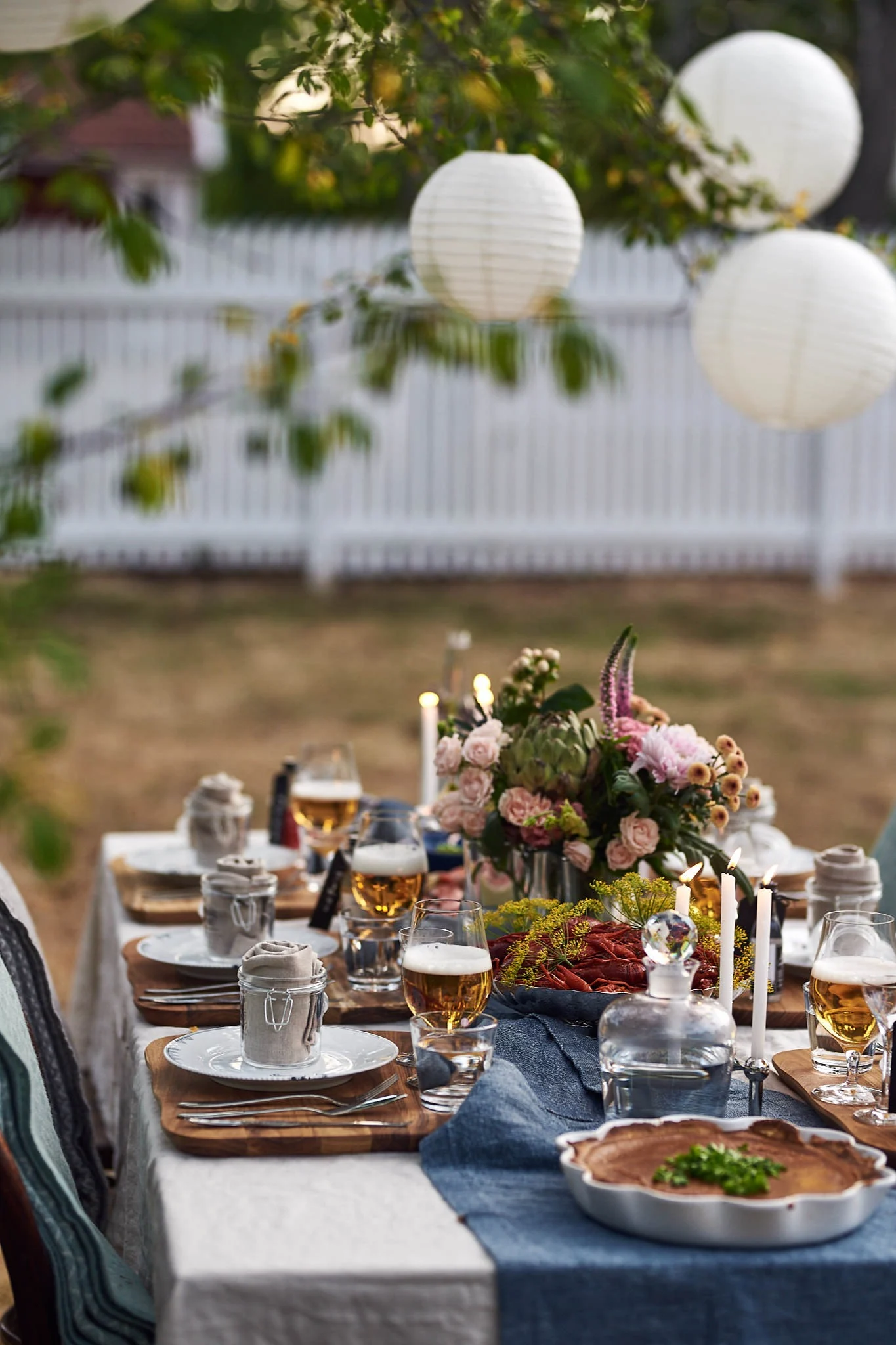 Kräftskiva: Decken Sie für das Krebsfest einen Tisch im Freien und dekorieren Sie mit Lampions, Tellern und Blumen.
