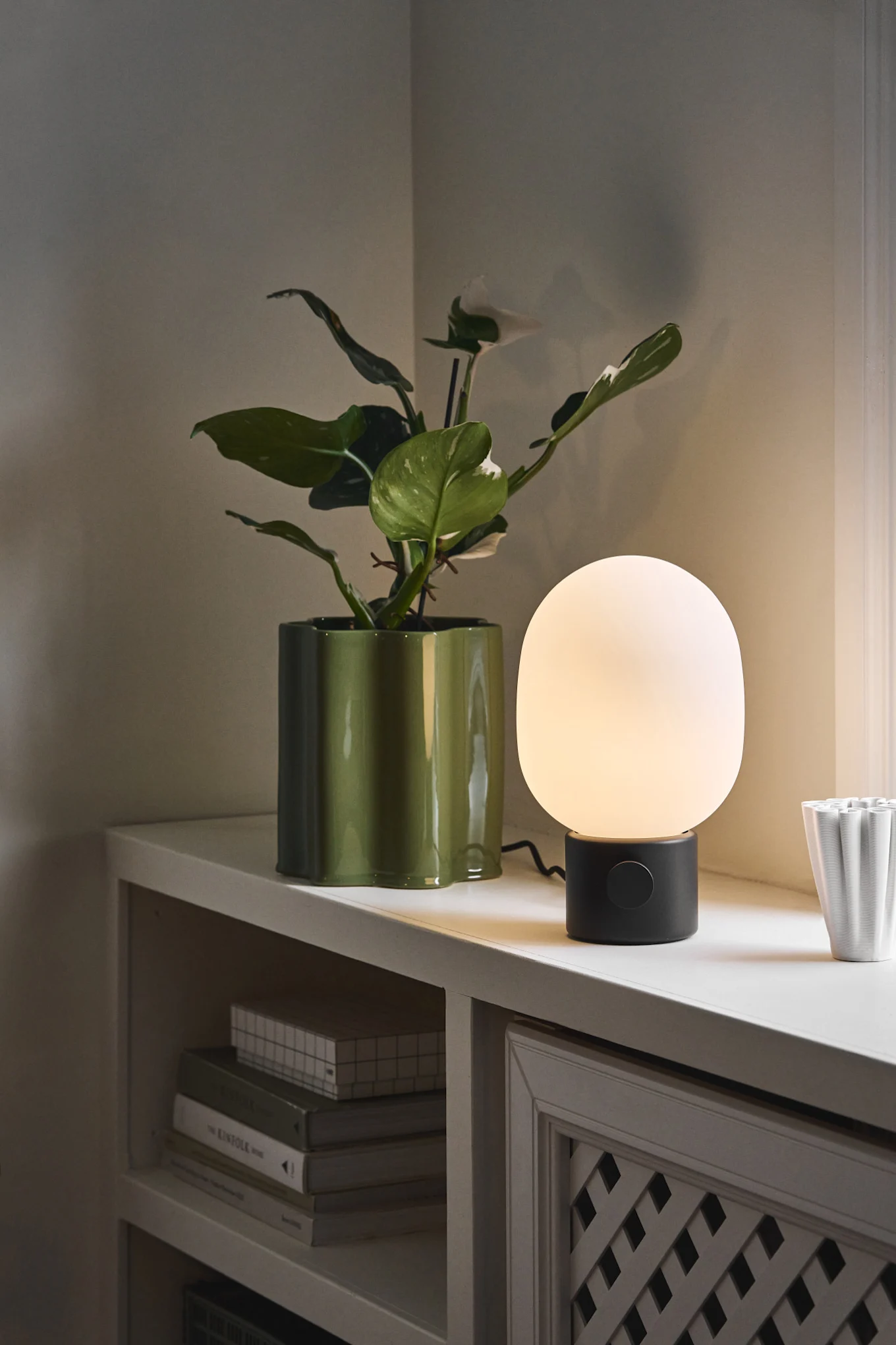 Skandinavische Lampen: Die JWDA-Tischleuchte von Audo Copenhagen steht neben einem Blumentopf auf einer Fensterbank.