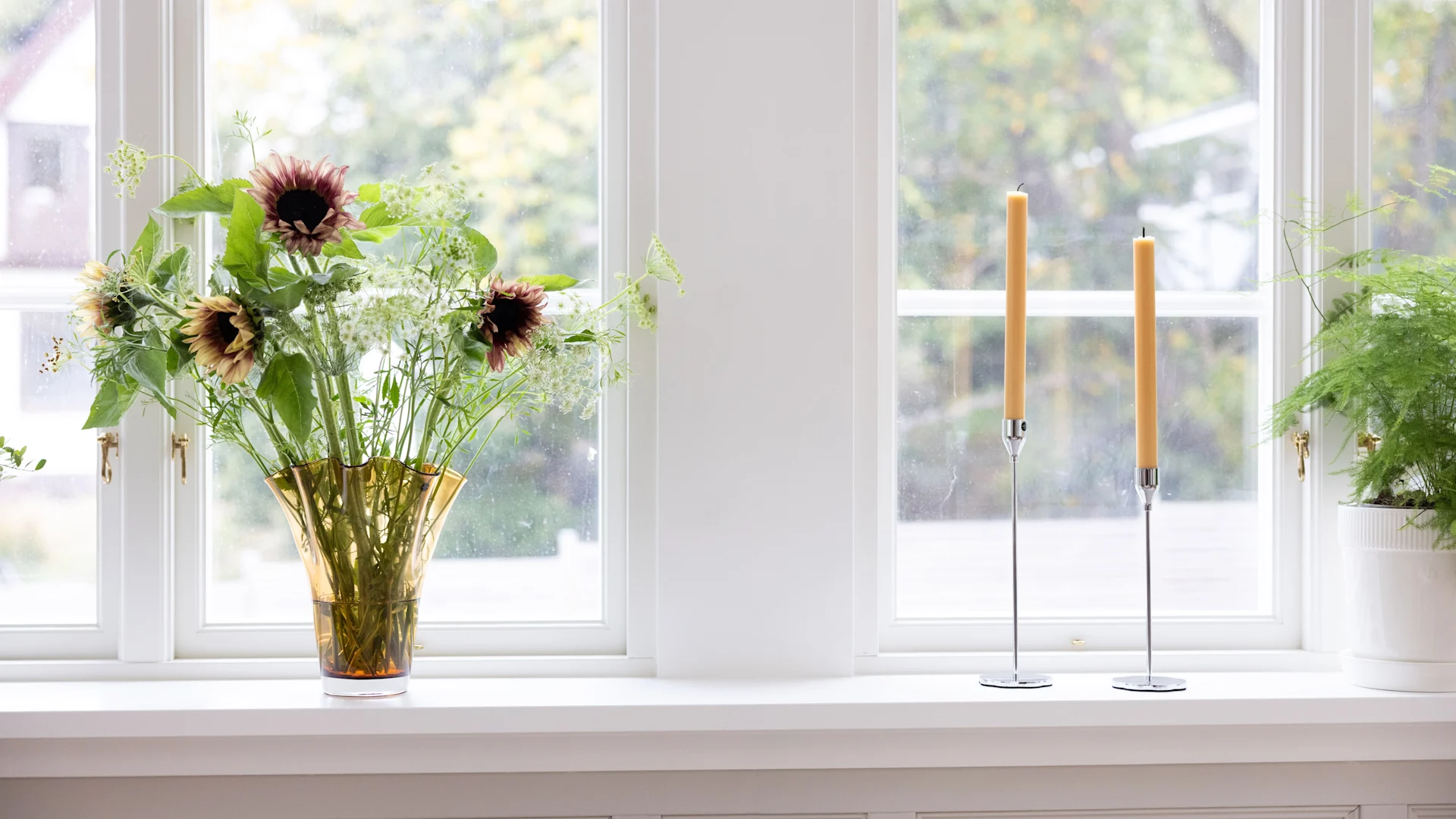 Dekorieren Sie Ihre Fensterbank, indem Sie verschiedene Objekte mit unterschiedlichen Größen und Höhen in Gruppen organisieren, so beispielsweise eine Tischleuchte, Vasen mit Blumen und Kerzenhalter.