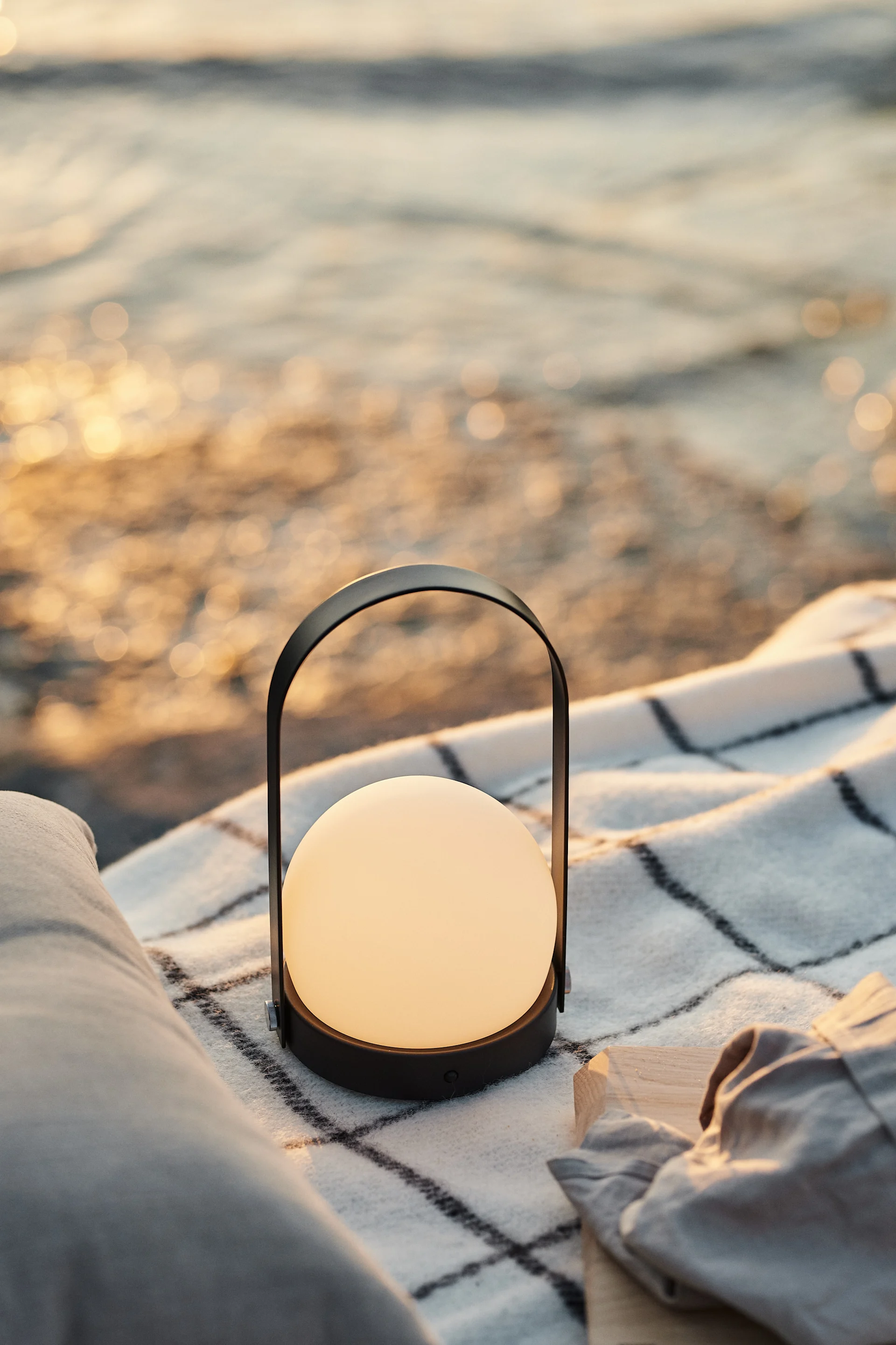 Diese tragbare Lampe von Menu, die Sie bei Sonnenuntergang schön auf der Picknickdecke am Strand platzieren können, um eine entspannte Atmoshäre zu erzeugen.