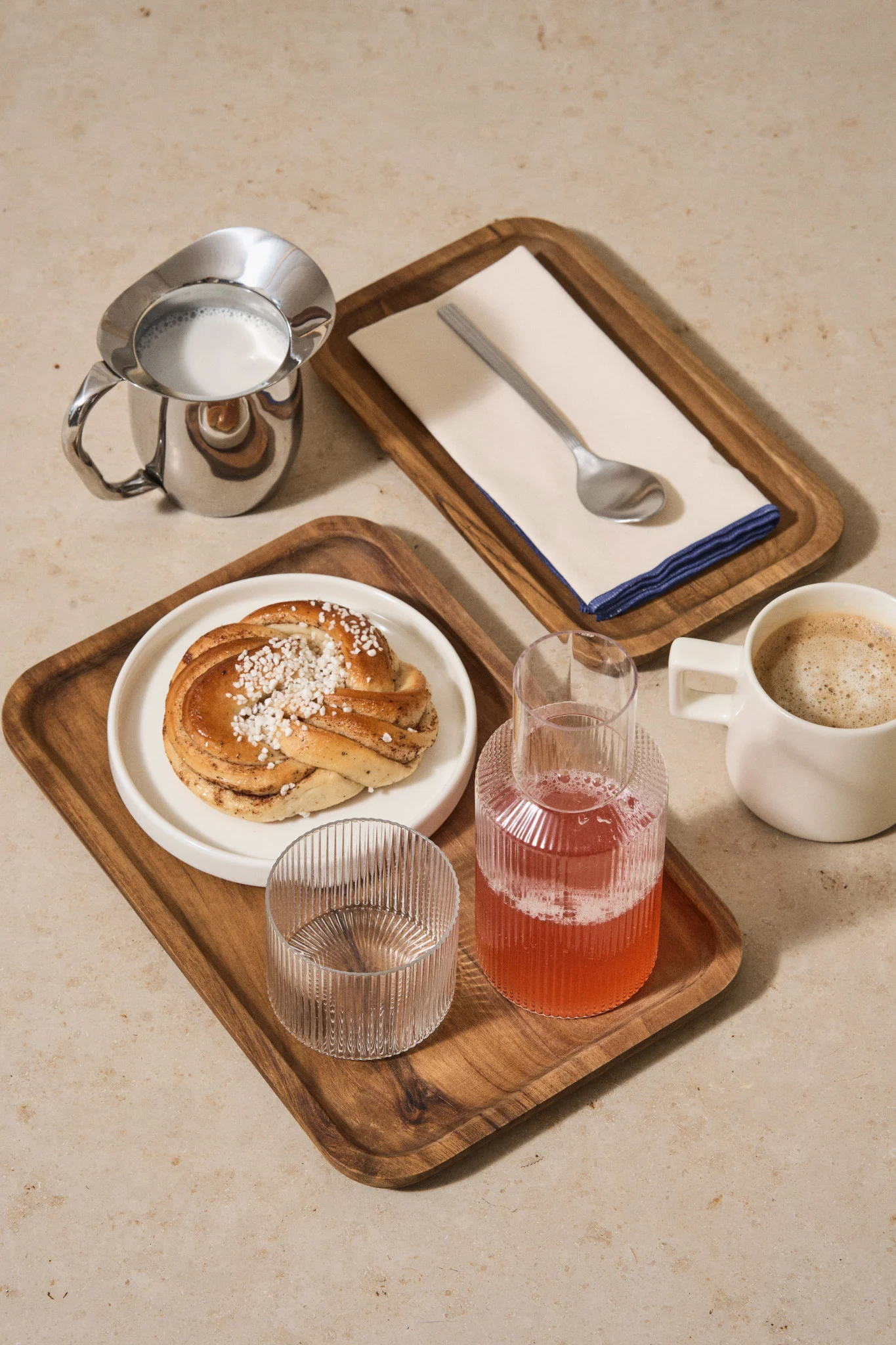 Schwedisches Gebäck: Eine perfekt geformte Zimtschnecke liegt auf einem Teller, daneben stehen Kaffee und Saft für eine Fika bereit.