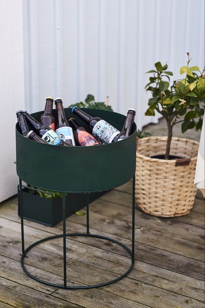 Die runde Blumenkiste Plant Box von Ferm Living bekommt eine neue Funktion als Getränkestation auf der Party, die mit Flaschen gefüllt wird.