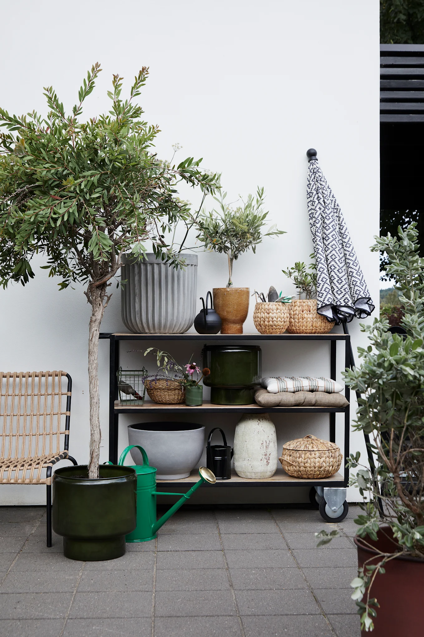Viele Pflanzen sorgen für den passenden Boho-Look auf Ihrem Balkon. Hier sehen Sie einen Pflanzenständer mit mehreren Blumen in Blumentöpfen von House Doctor.