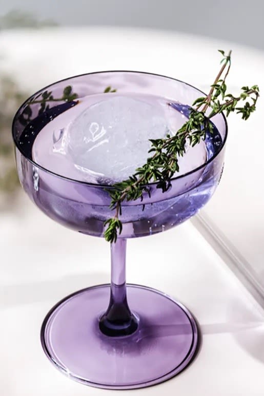 Farbtrends 2024: Zu den Trendfarben des Jahres zählt auch Lavendel. Hier sehen Sie das lavendelfarbene Like-Champagnerglas von Villeroy & Boch mit einem Cocktail darin und mit Rosmarin dekoriert.