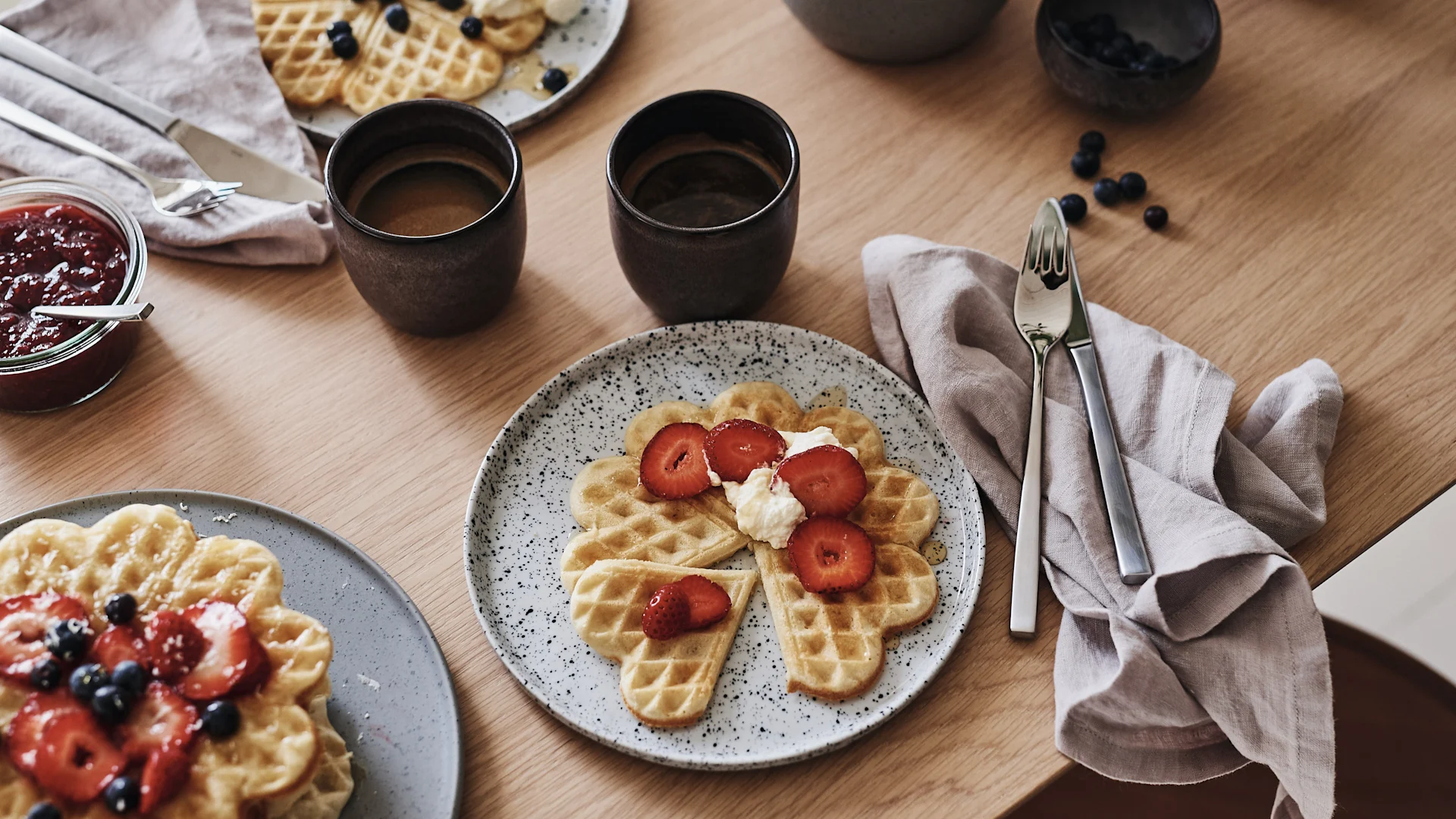 Der Tisch ist mit Waffeln auf einem rustikalen Teller gedeckt und eine Leinenserviette liegt auf dem Tisch.