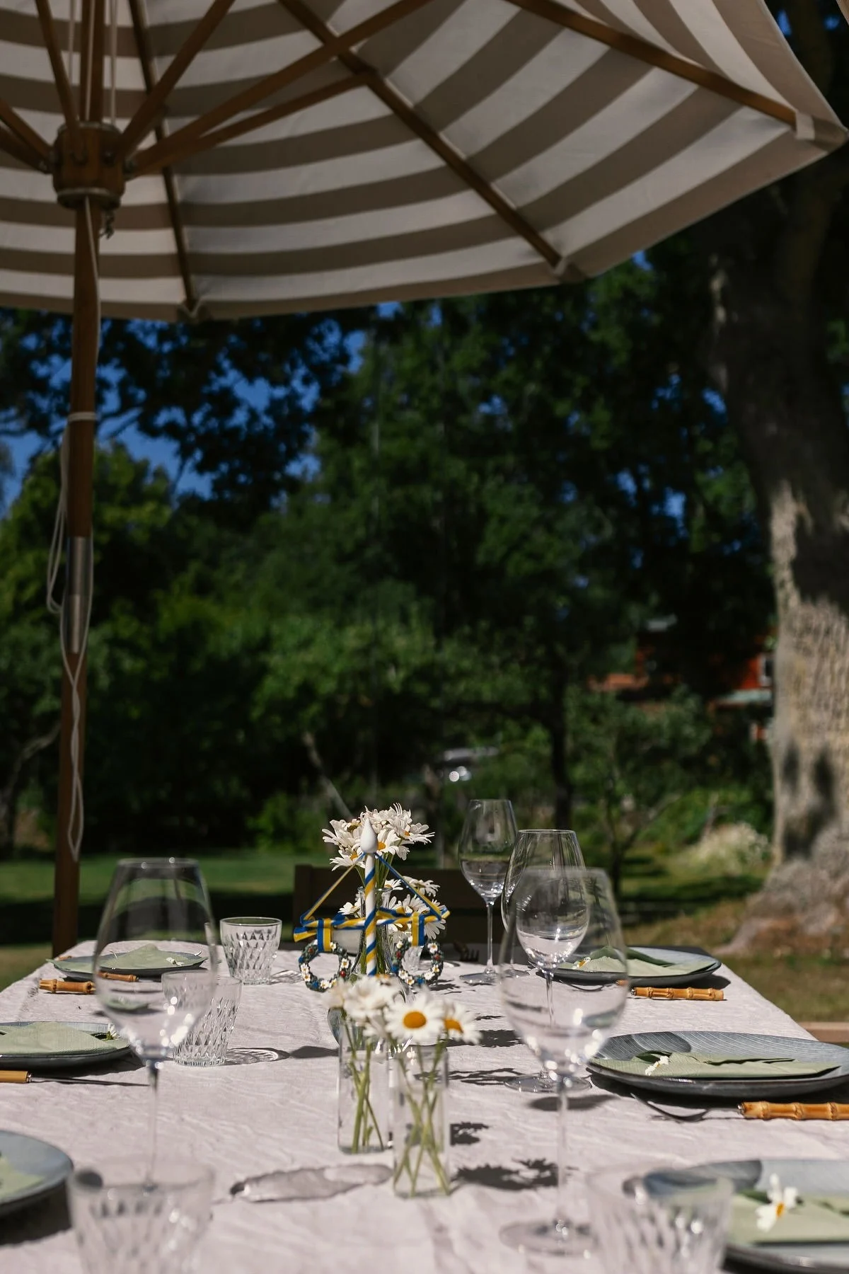Eine minimalistische Tischdeko zu Mittsommer mit einem schlicht gedeckten Tisch in Weiß, kleinen Vasen und Broste Copenhagen Tellern im Garten von @applaudden.