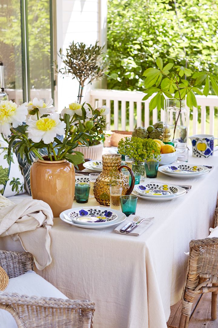 Decken Sie den Tisch für den Mittsommer in einem mediterran inspirierten Stil mit gelben Details, Pfingstrosen auf dem Tisch und grünen Gläsern von Iittala. 