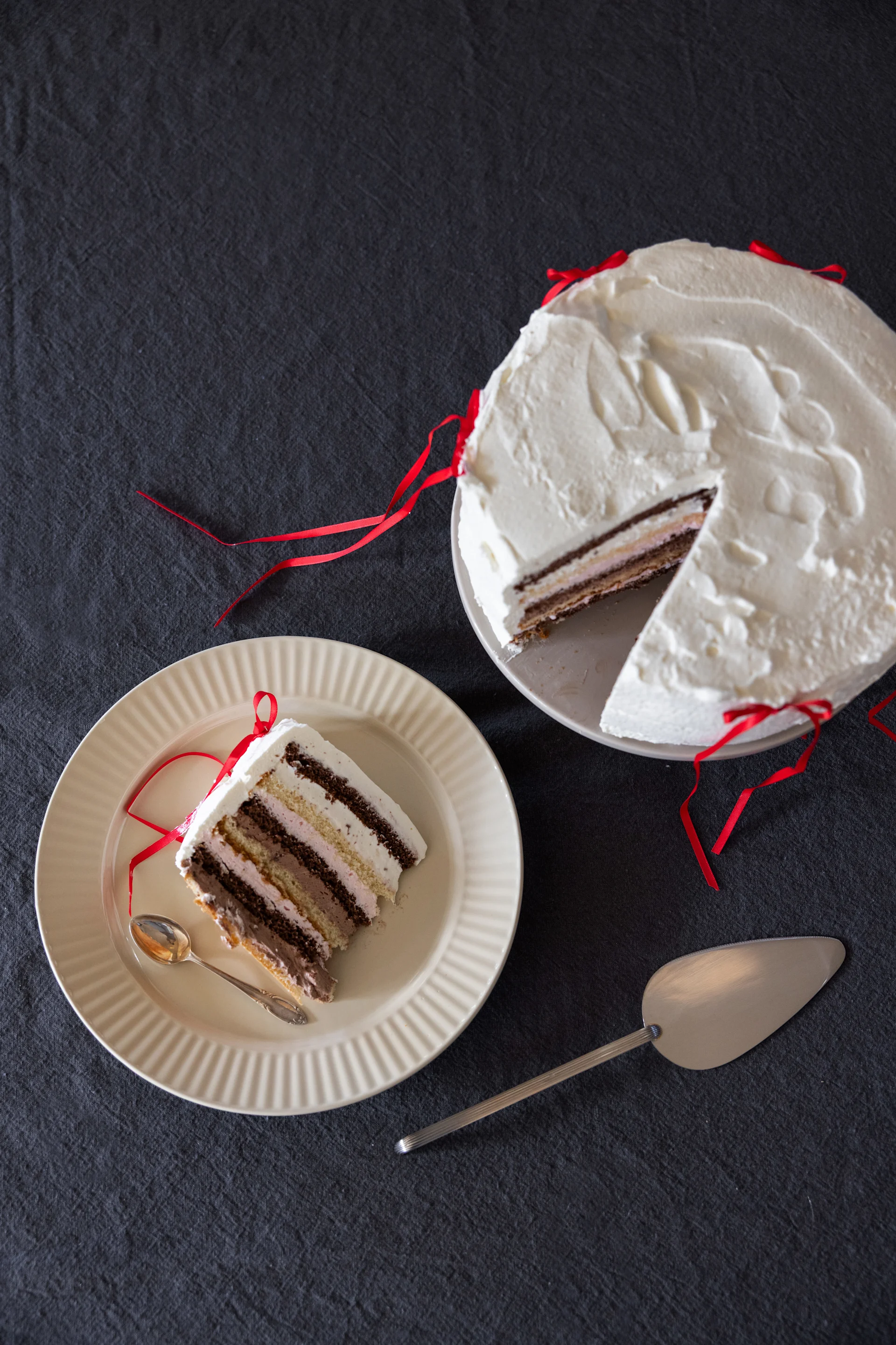 Eine Sahnetorte auf einem Teller, daneben ein Stück Torte auf einem weiteren Teller aus der Coffee & more-Kollektion von Sagaform in Beige.