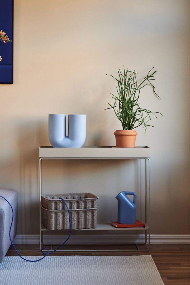 Dekorieren Sie Ihr Wohnzimmer mit beigen Möbeln in Kombination mit Farbe für einen lebendigen Look in Ihrem Zuhause. Hier sehen Sie den vielseitigen und praktischen Plant Box Konsolentisch von Ferm Living in Beige zusammen mit der blauen Vase Kink und dem Tub Krug von Muuto.