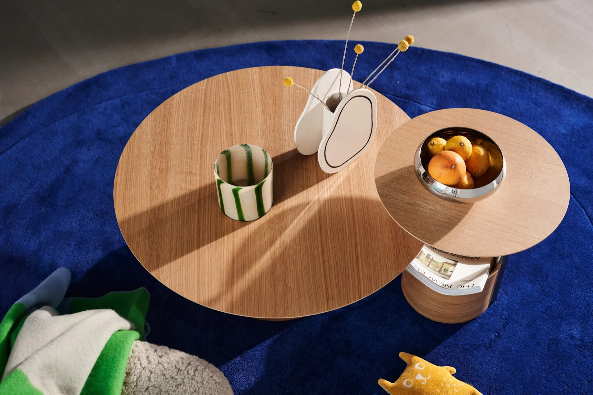 Die Parasol-Tische von oben auf einem blauen Teppich mit einer Vase und einer Schale mit Orangen und Zitronen.