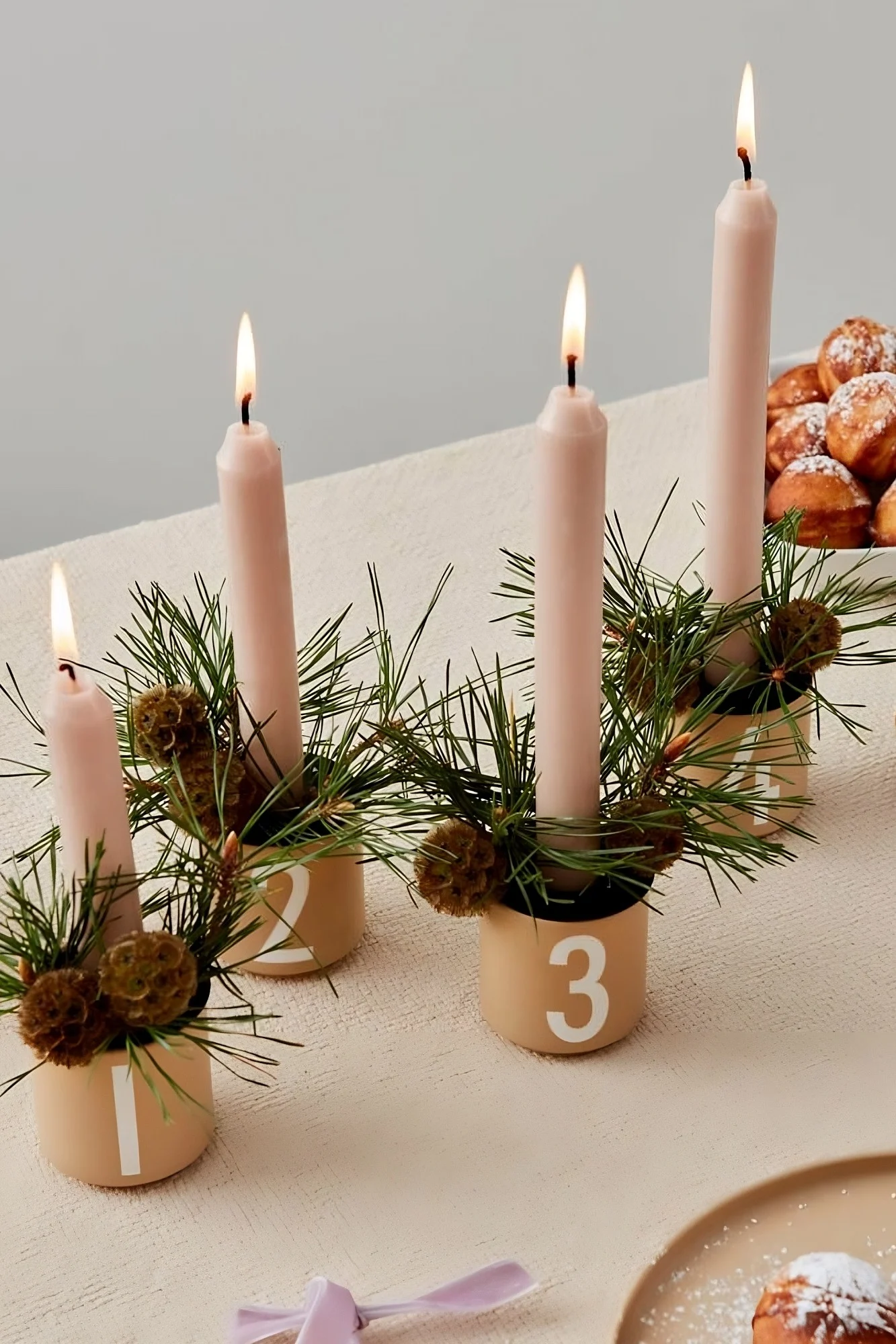 Auf einem Tisch stehen die vier Espressotassen von Design Letters, dekoriert als weihnachtliche Kerzenhalter.