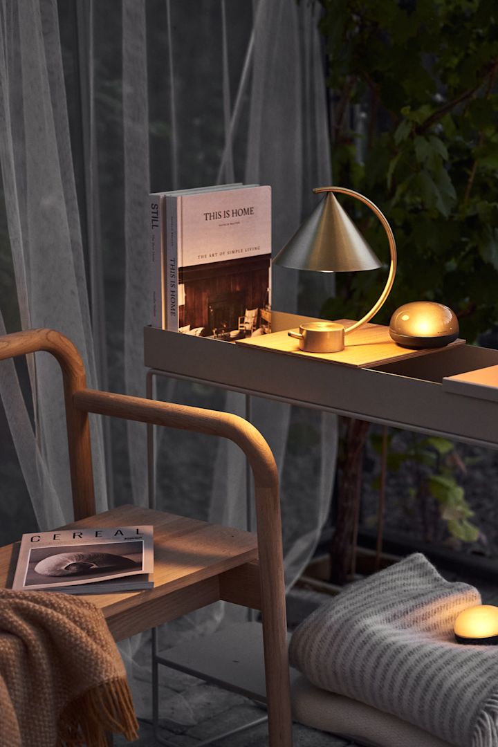 Eine Leseecke ist einer der Einrichtungstrends im Herbst 2021. Hier ist die tragbare Lampe Meridian aus Messing von Ferm Living.