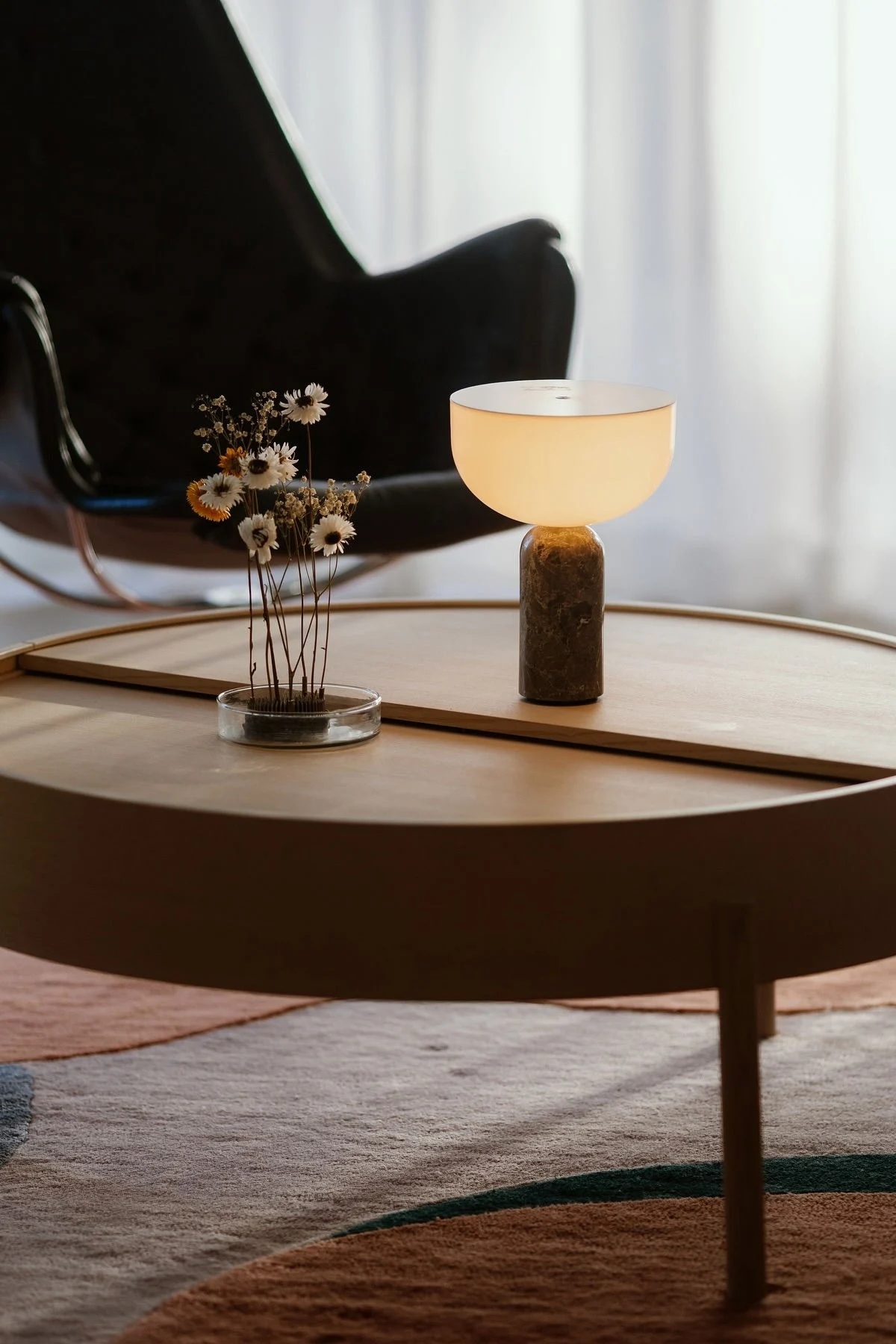 Der Arc Couchtisch von Woud ist dekoriert mit einer Kizu Tischleuchte von New Works und dem Garden Glory Blumenigel.