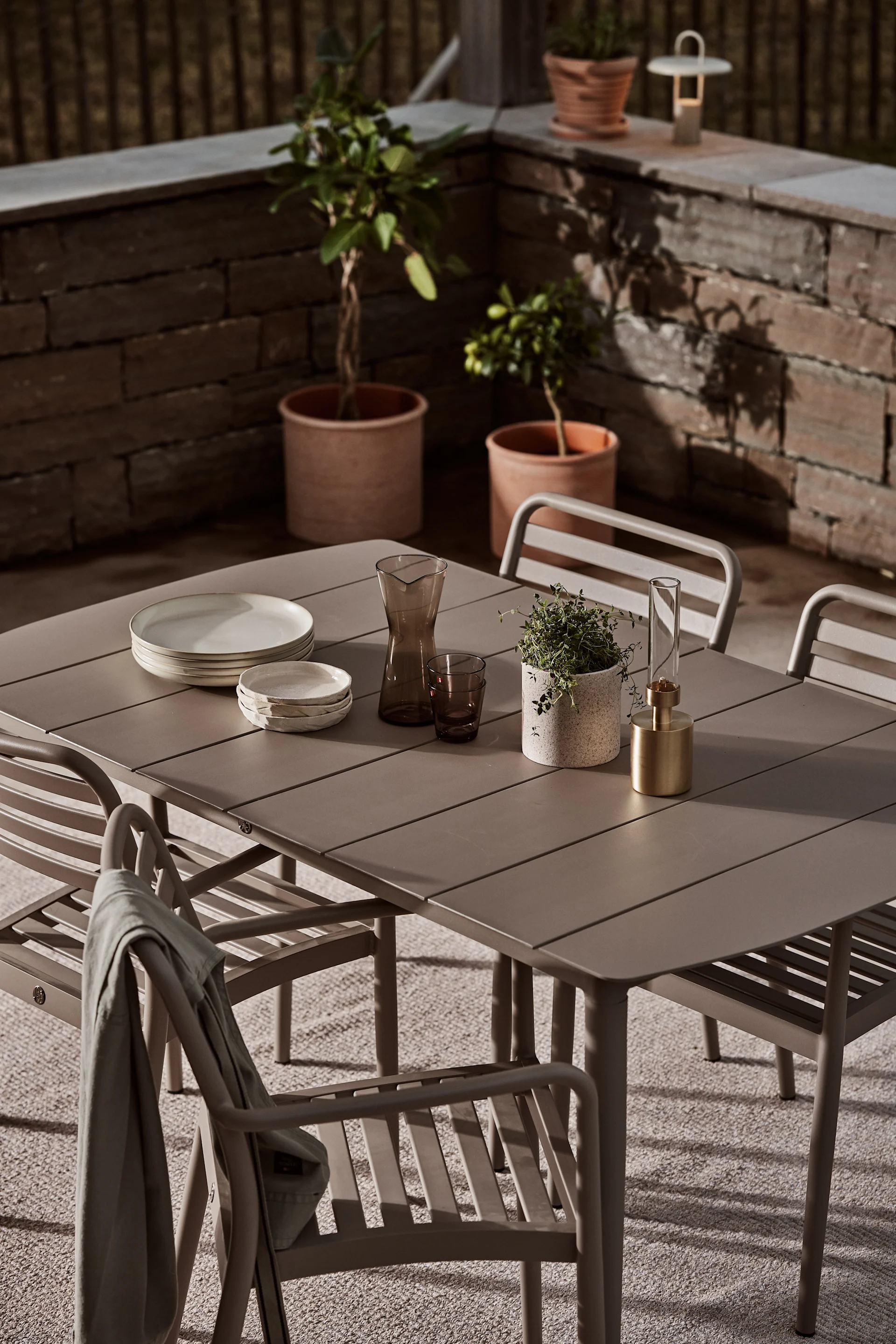 Mit dem Taupe-Farbton und den geschwungenen Formen passen die Stühle aus der Messina-Kollektion und der Marsala Tisch, beides von 1898 und auf einer Terrasse stehend, optimal in die diesjährigen Gartenmöbel-Trends.