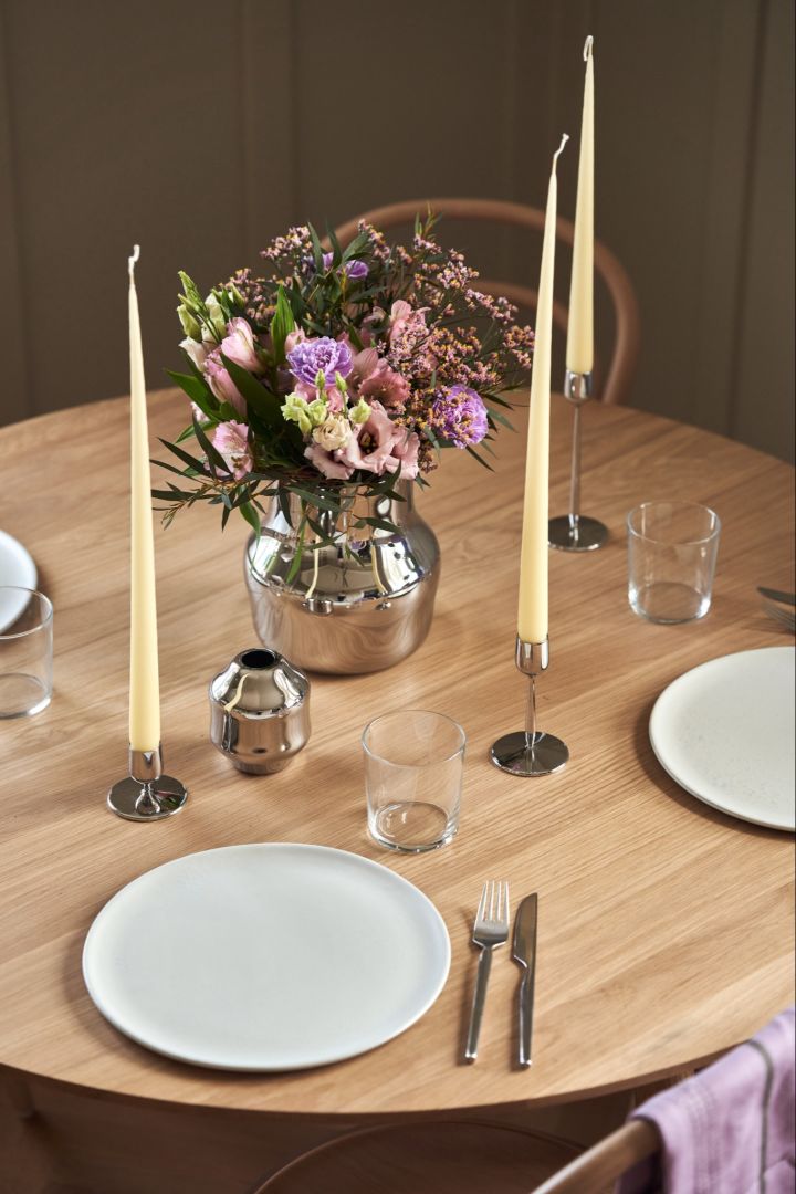 Eine elegante Tischdekoration mit einer Vase aus poliertem Edelstahl aus der Dorotea-Kollektion für Gense und passenden Kerzenständern. 