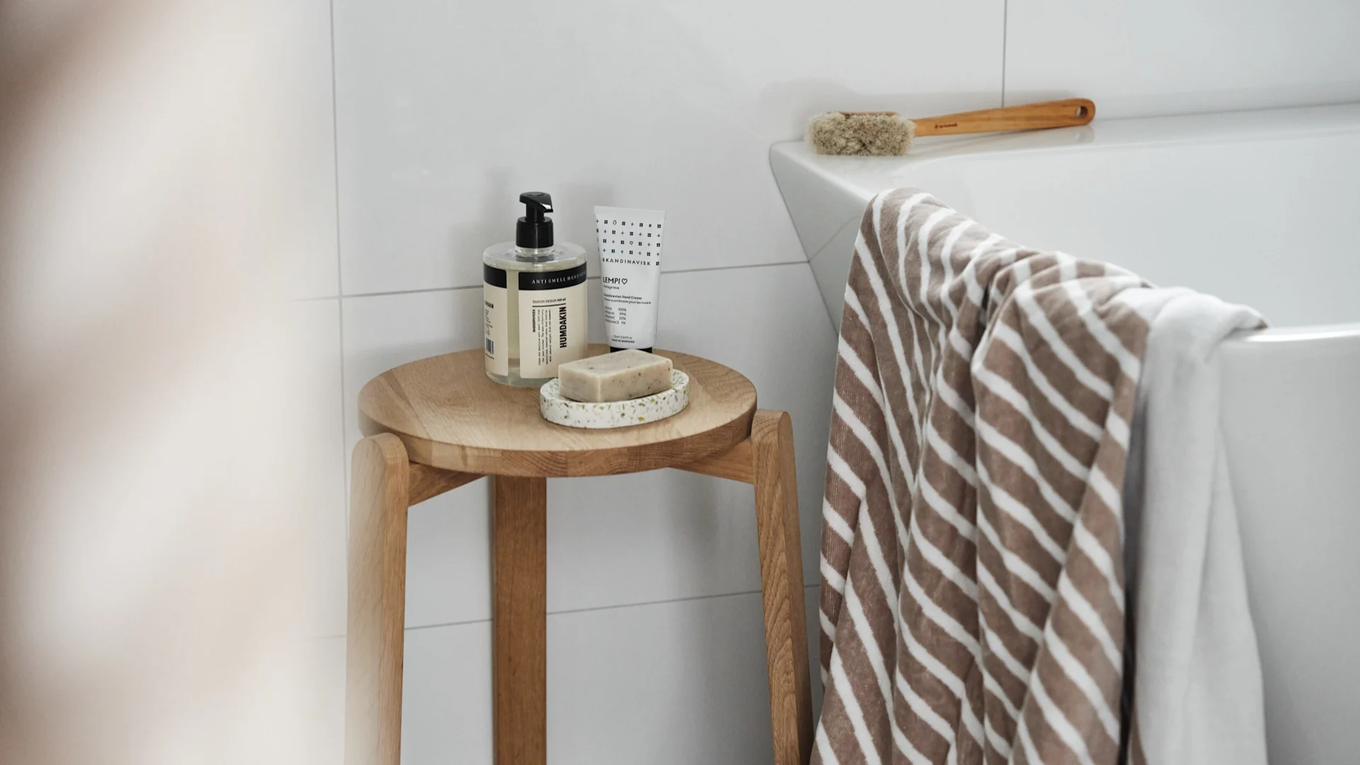 Geschenk zum Valentinstag: Machen Sie einen Spa-Tag und schenken Sie die notwendigen Utensilien. Hier hängt das Stripes-Badetuch von NJRD über einer Badewanne, daneben steht ein Hocker mit Seife und Seifenteller von Humdakin.