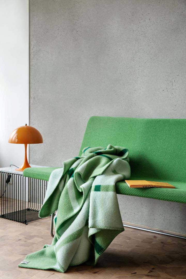 Wohntrends des Frühlings 2024: Auch farbenfrohe Textilien zählen zu den Wohntrends des Frühlings 2024, daher dekorieren wir gern mit der grün gemusterten Knut-Decke von Røros Tweed.