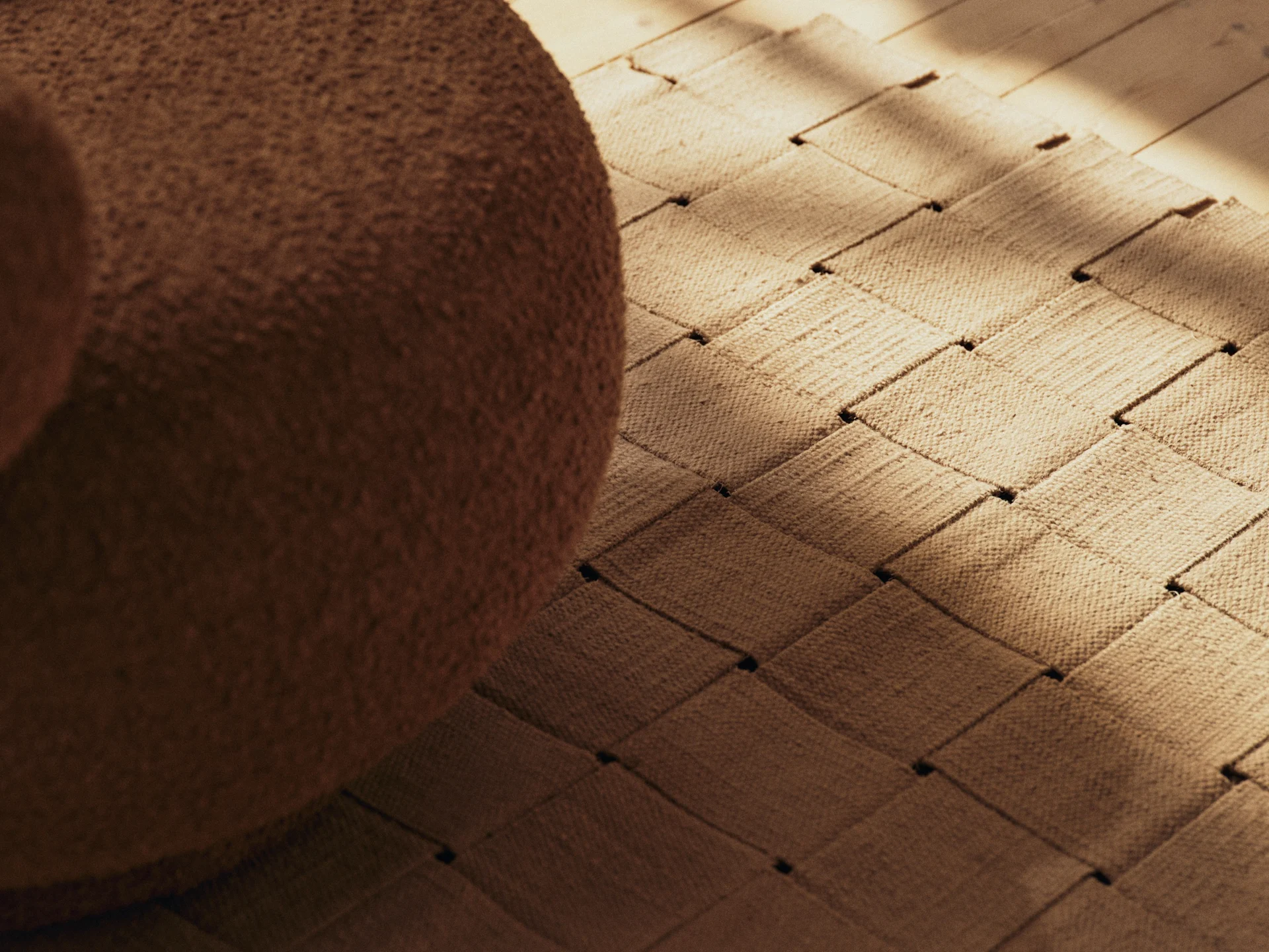 Braune Bouclé-Möbel, ein gewebter Teppich und ein Holzboden mit sonnenbeschienenen Schatten.