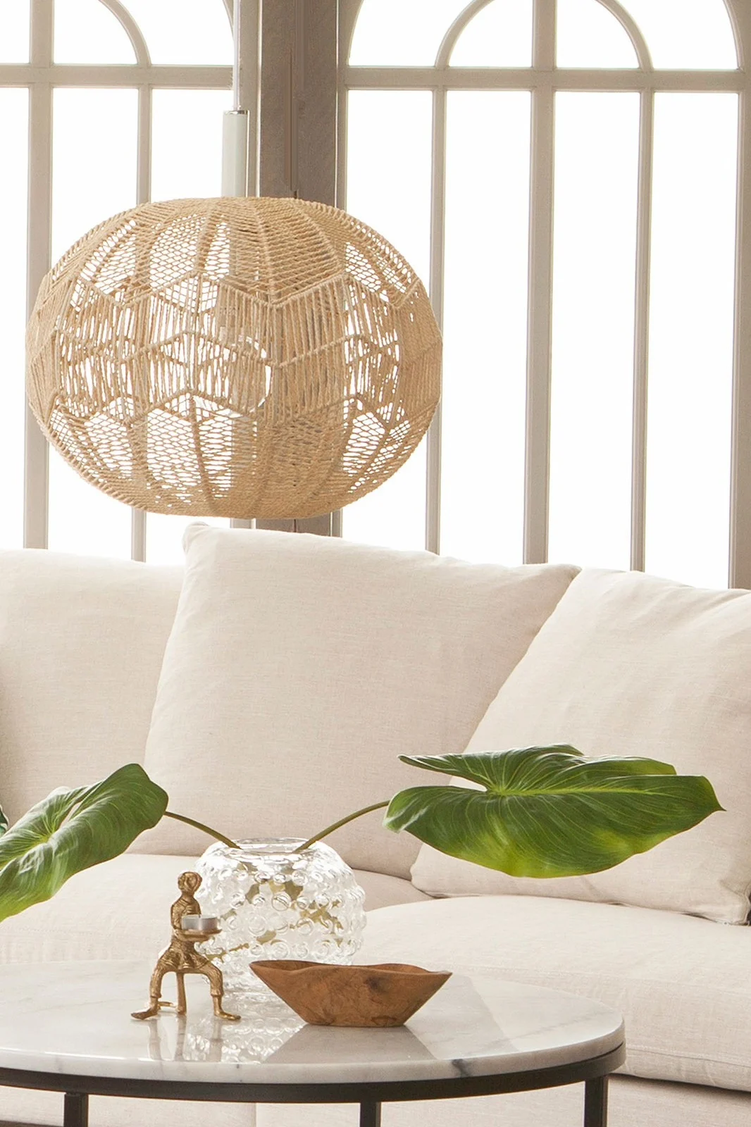 Die Missy Pendelleuchte von Globen Lighting aus Rattan hängt in einem hellen Wohnzimmer und ist dank ihres Materials die perfekte Boho Deko.