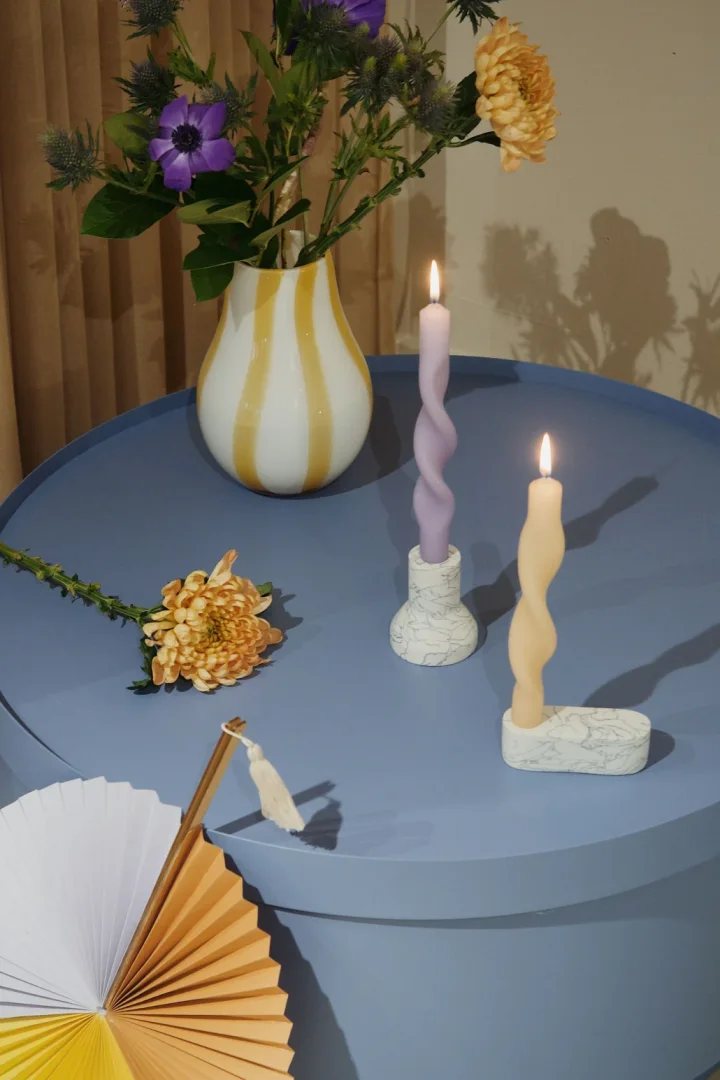 Gedrehte Kerzen in Lavendel und Zitronengelb auf einem himmelblauen Tisch – Broste Copenhagen zeigt uns die Farbtrends für 2022.