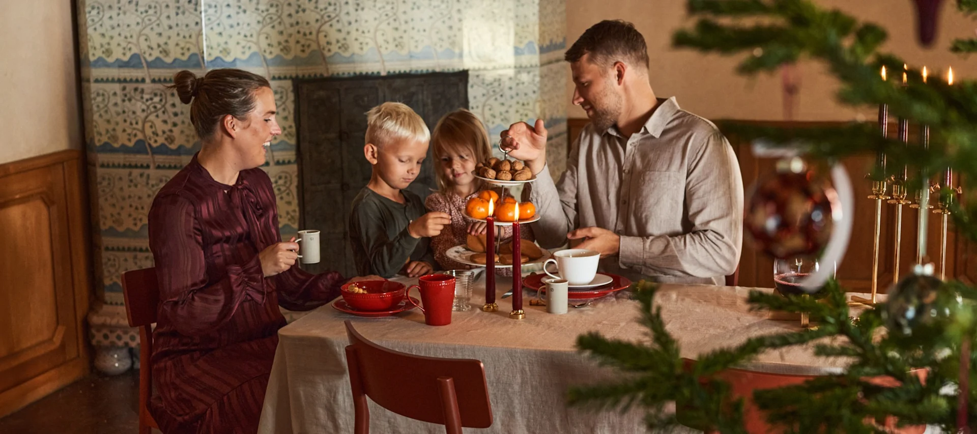 Eine Familie mit zwei Kindern sitzt an einem weihnachtlich gedeckten Tisch.