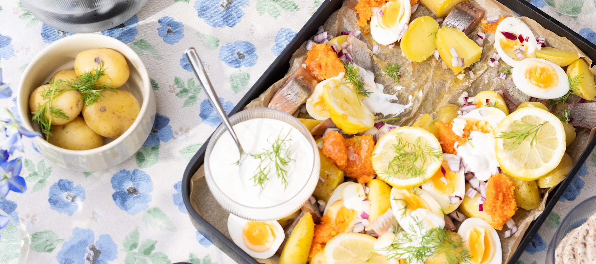Sommer-Rezepte: Ein schwedischer Kartoffelsalat mit Ei und Matjes auf einem Tisch, daneben Kartoffeln.