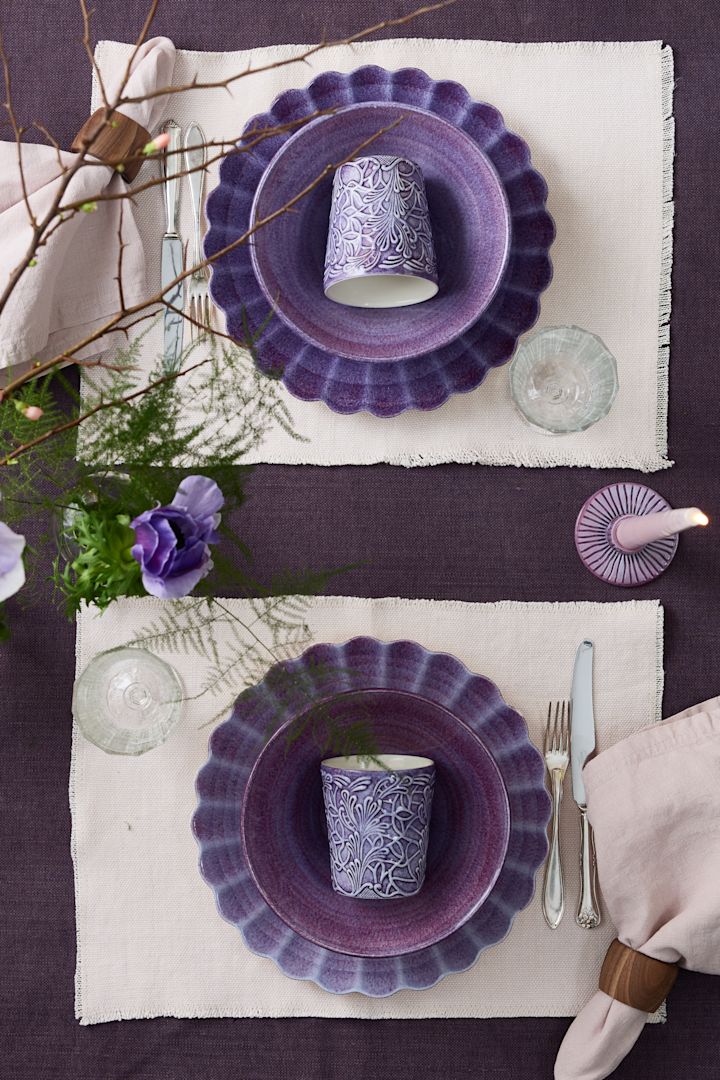Zwei gegenüberliegende Tischgedecke in Violett, im Fokus der Lace-Becher von Mateus.