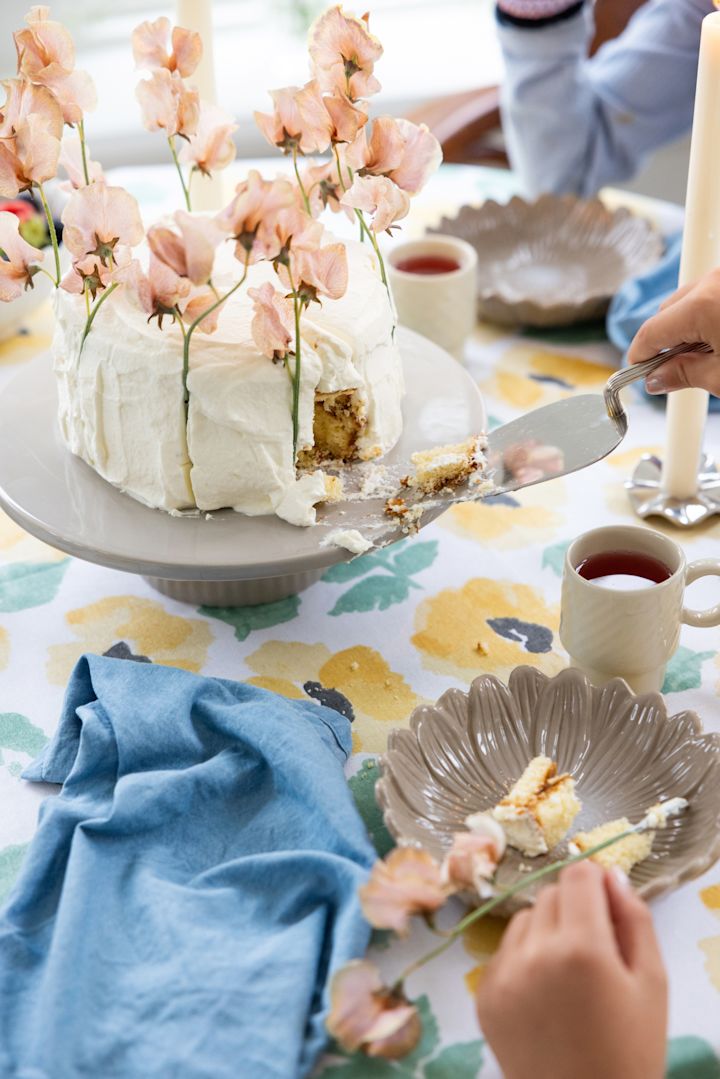 Ein bunter, frühlingshaft gedeckter Tisch mit einer großen Torte, alles von Sagaform.