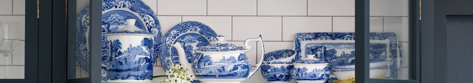 Blau-weiß gemustertes Porzellan-Geschirrset mit Teekanne, Tellern und Schalen in einem dunkelblauen Schrank.