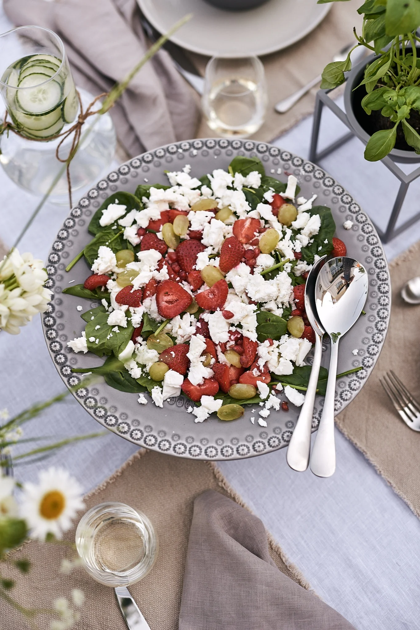 Ein herrlicher Sommersalat mit Erdbeeren und Fetakäse, serviert auf einer grauen Kuchenplatte, ist der Hauptgang des sommerlichen Mittagessens.