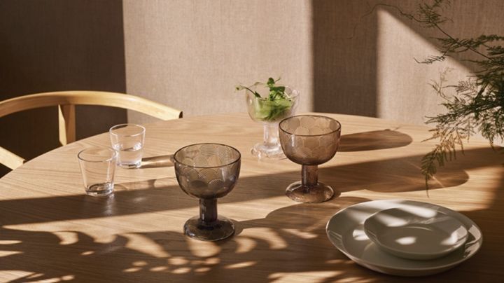 Gläser, Teller und Schalen von Iittala in schönem Tageslicht stehen auf dem Tisch. 