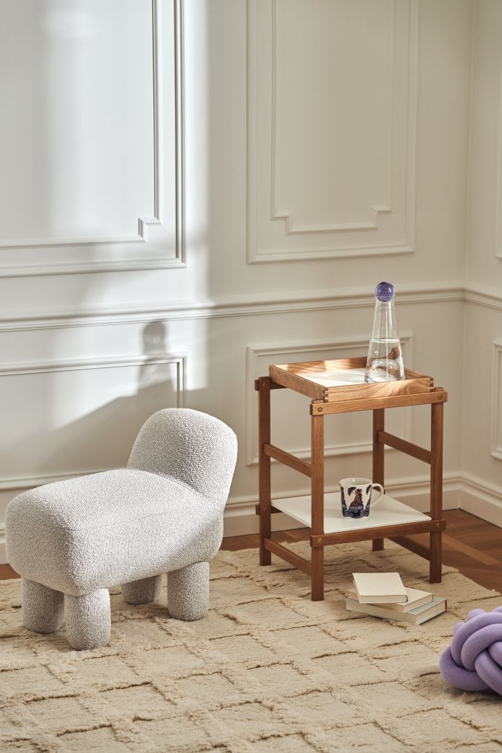 Ein stylischer Raum, der mit Produkten von Design House Stockholm ausgestattet wurde. Darunter der Lulu Pouf, ein Holzregal, das Knot Kissen in Lilac und eine Elsa Beskow Tasse.