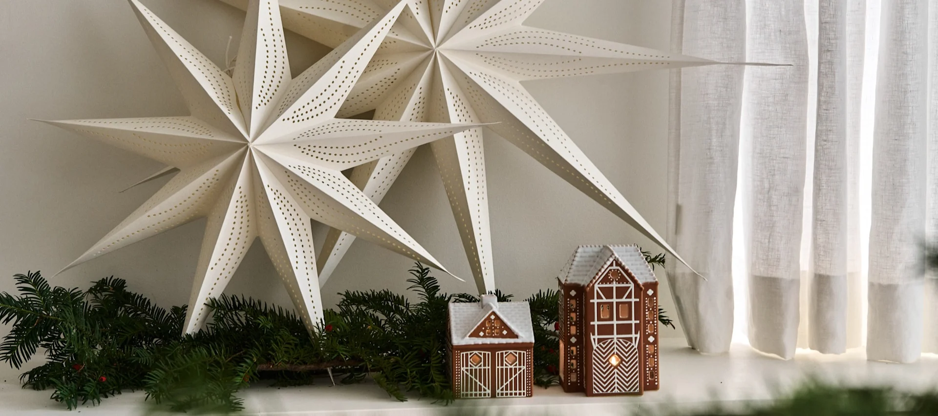 Weihnachtsdeko modern in einem skandinavischen Wohnzimmer. Hier sehen Sie zwei skandinavische Weihnachtssterne in einem neutral gehaltenen Wohnzimmer mit zwei Lebkuchenhäuschen.