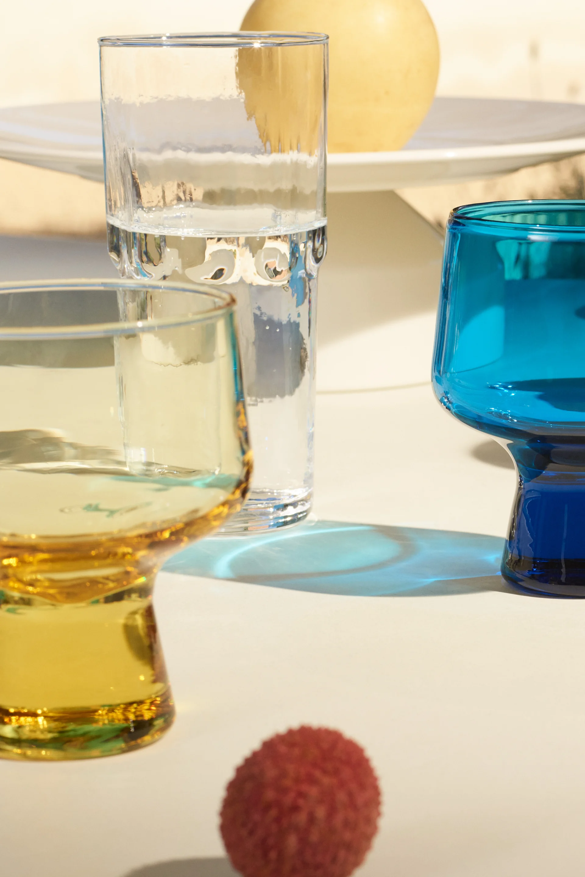 Die neue Solare-Kollektion von Iittala, hier sehen Sie die gelben, blauen und klaren Gläser der Kollektion im Sonnenschein leuchten. 