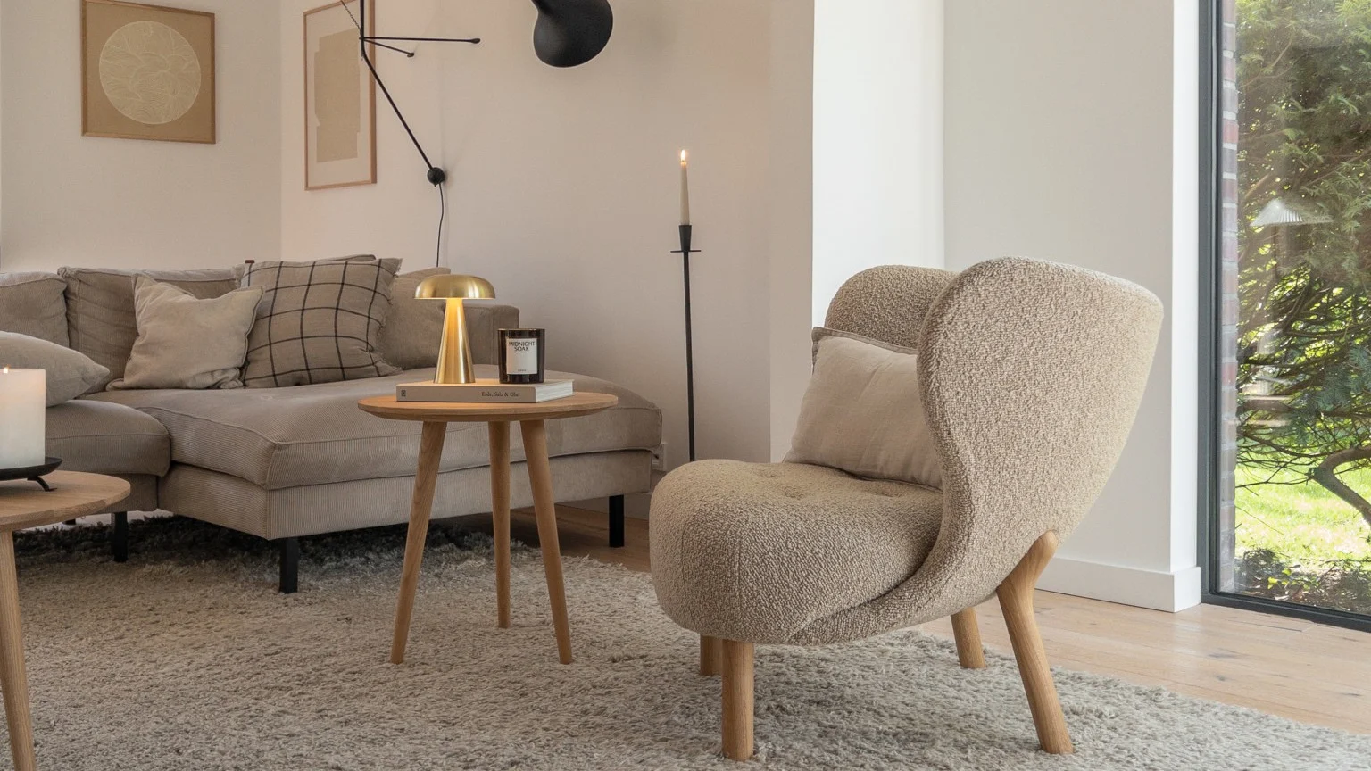 Das beigefarbene Wohnzimmer von @haus_tannenkamp mit der goldenen Como Tischlampe und dem Little Petra Sessel, beides von &Tradition.