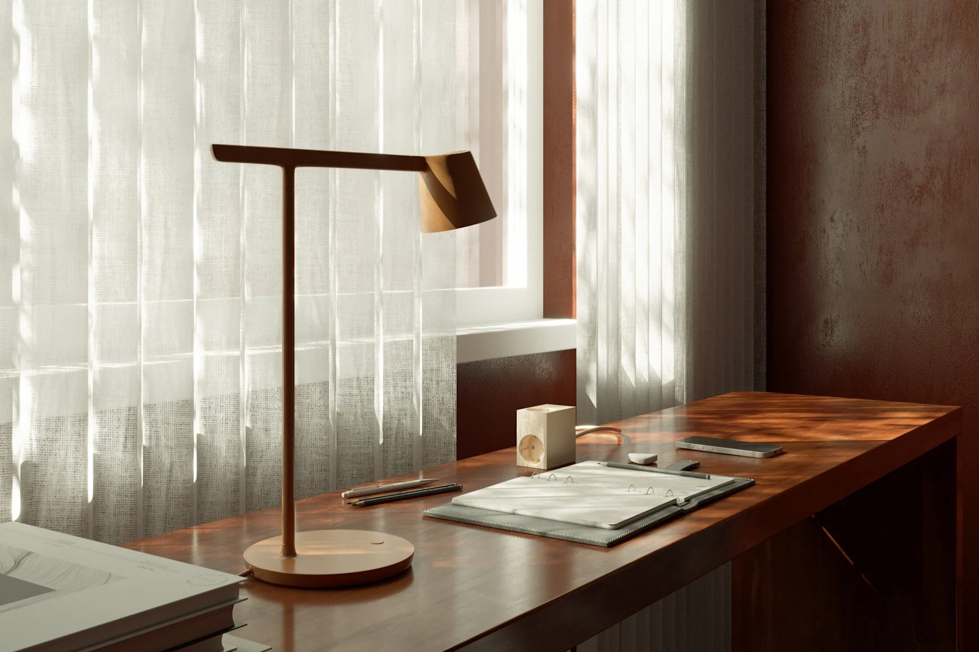 Ein Arbeitsplatz mit einer modernen Schreibtischlampe, Notizblock und Smartphone auf einem Holzschreibtisch an einem Fenster mit transparenten Vorhängen.