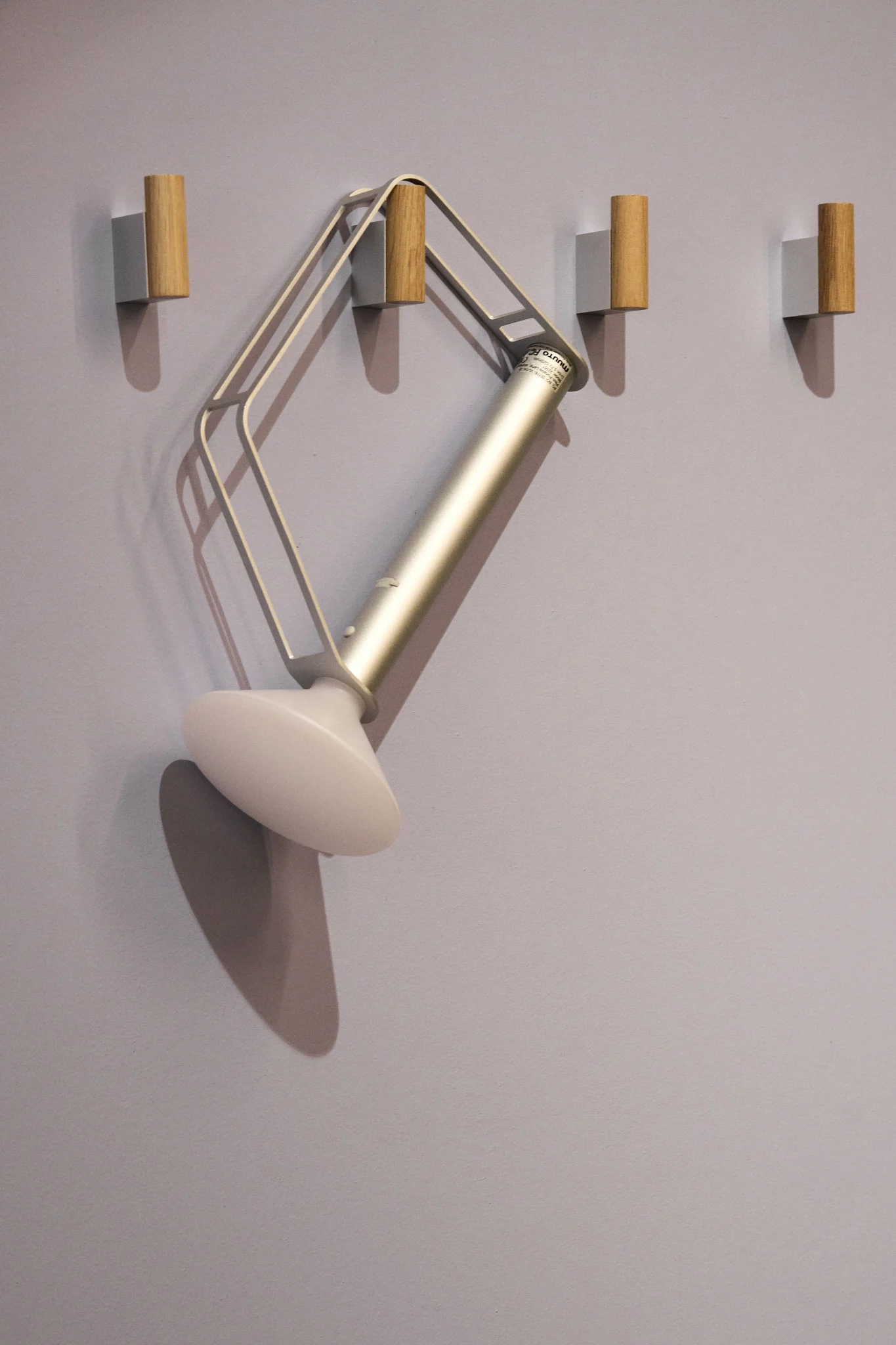 Die silberne, tragbare Piton Tischleuchte von Muuto hängt an einem von vier Haken an der Wand.