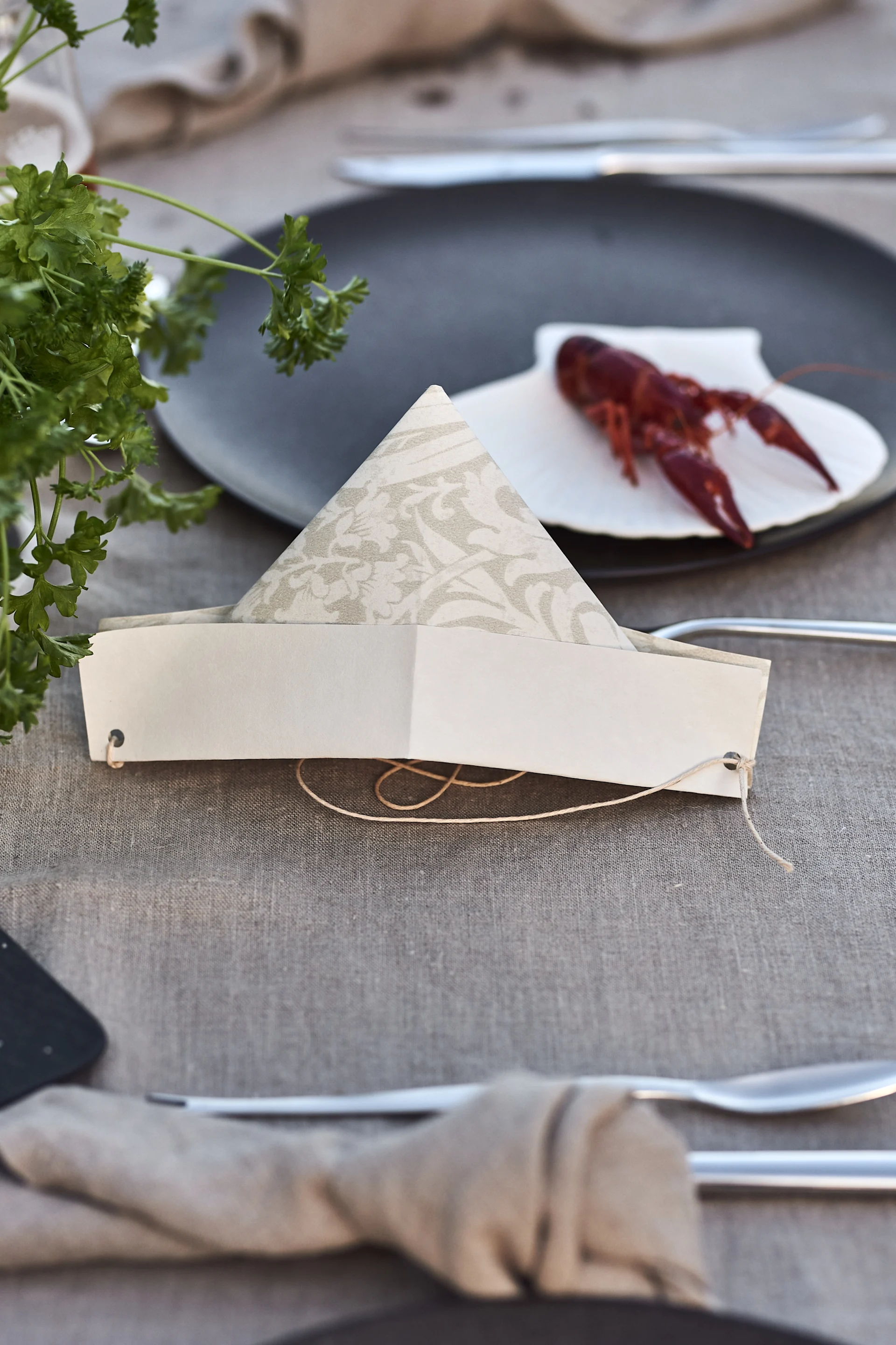 Eine lustige Aktivität für Ihre Kräftskiva ist das Basteln von Papierhüten, welche hier auf einem gedeckten Tisch liegen.