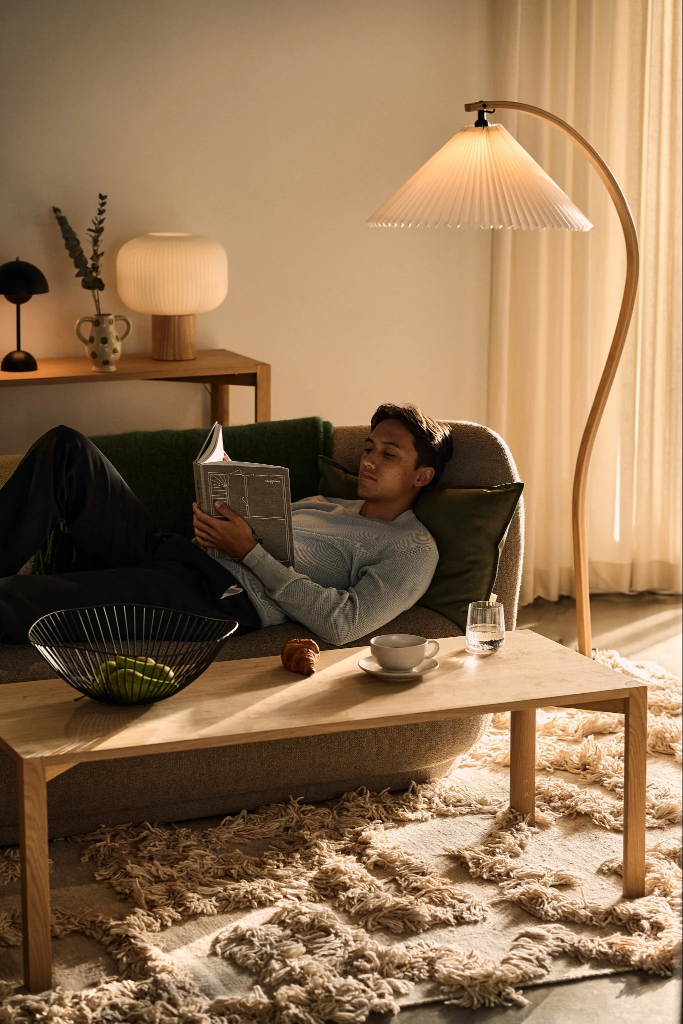 Für die perfekte Lichtgestaltung sollten vielfältige Optionen miteinander kombiniert werden - hier zum Beispiel die Timberline Stehleuchte von Gubi mit der Fair Tischleuchte von Scandi Living in einem gemütlichen Wohnzimmer.