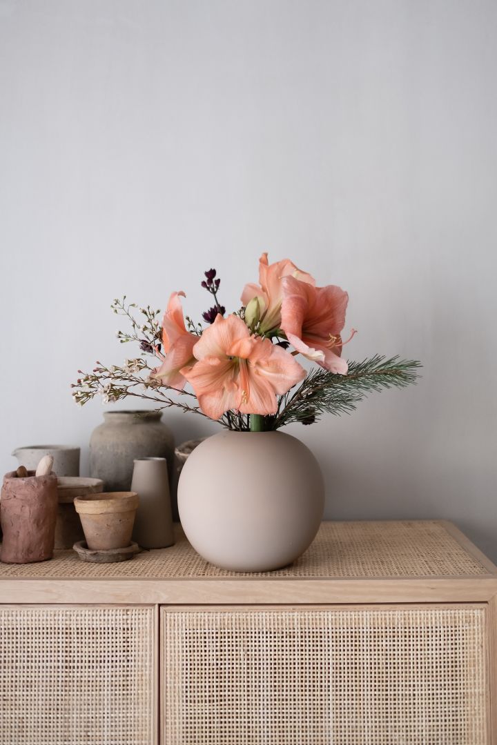 Eine hübscher Blumenstrauß in einer Vase von Cooee Design auf einer Rattankommode. So einfach können Sie ein Stillleben dekorieren.