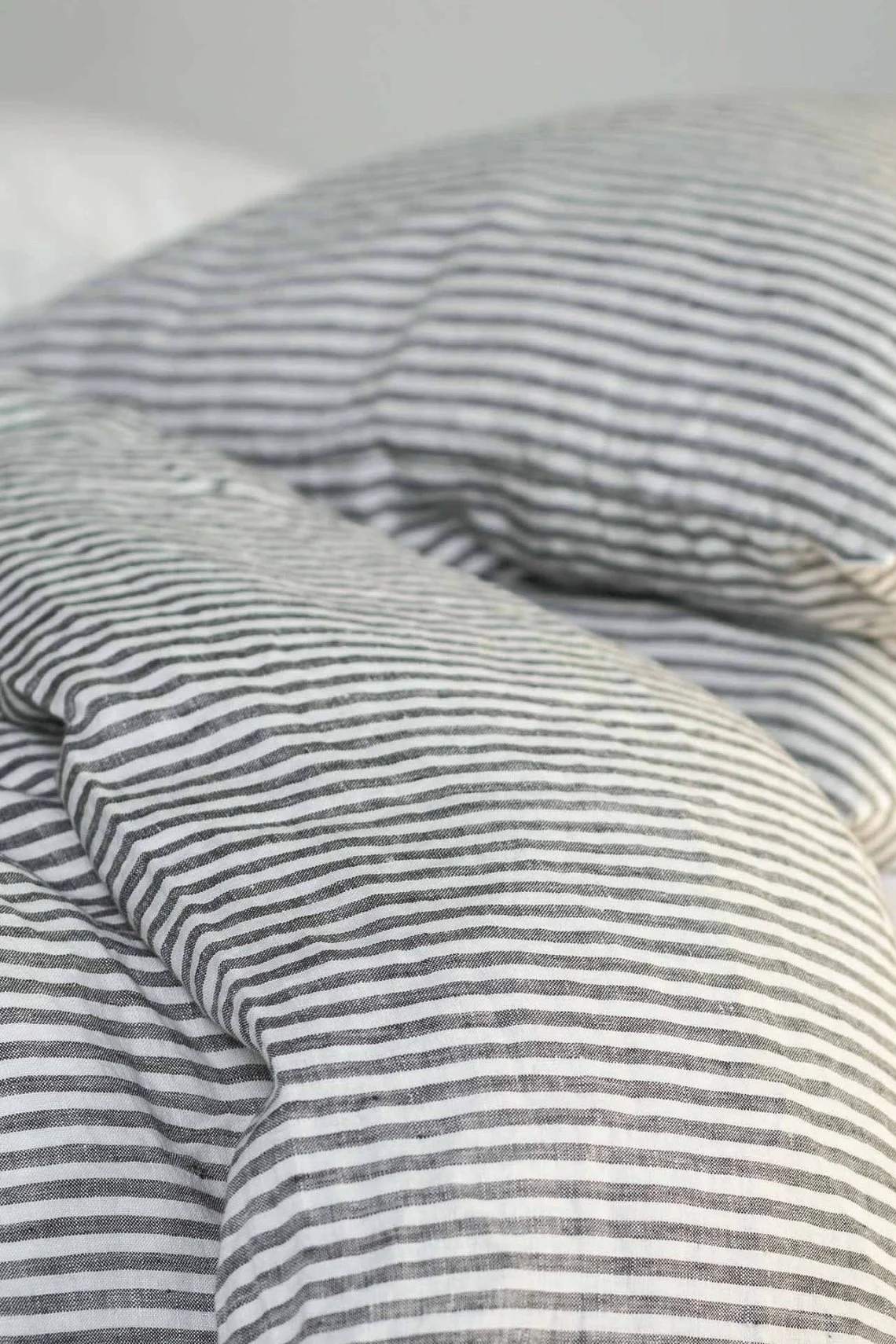 Nahaufnahme eines zerwühlten Bettes mit schwarz-weiß gestreifter Leinenbettwäsche.