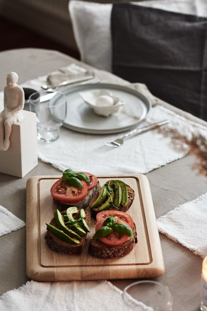 Ein leckeres Frühstück mit gesunden Sandwiches, das auf einem hellen Holzbrettchen von Skagerak serviert wird. 