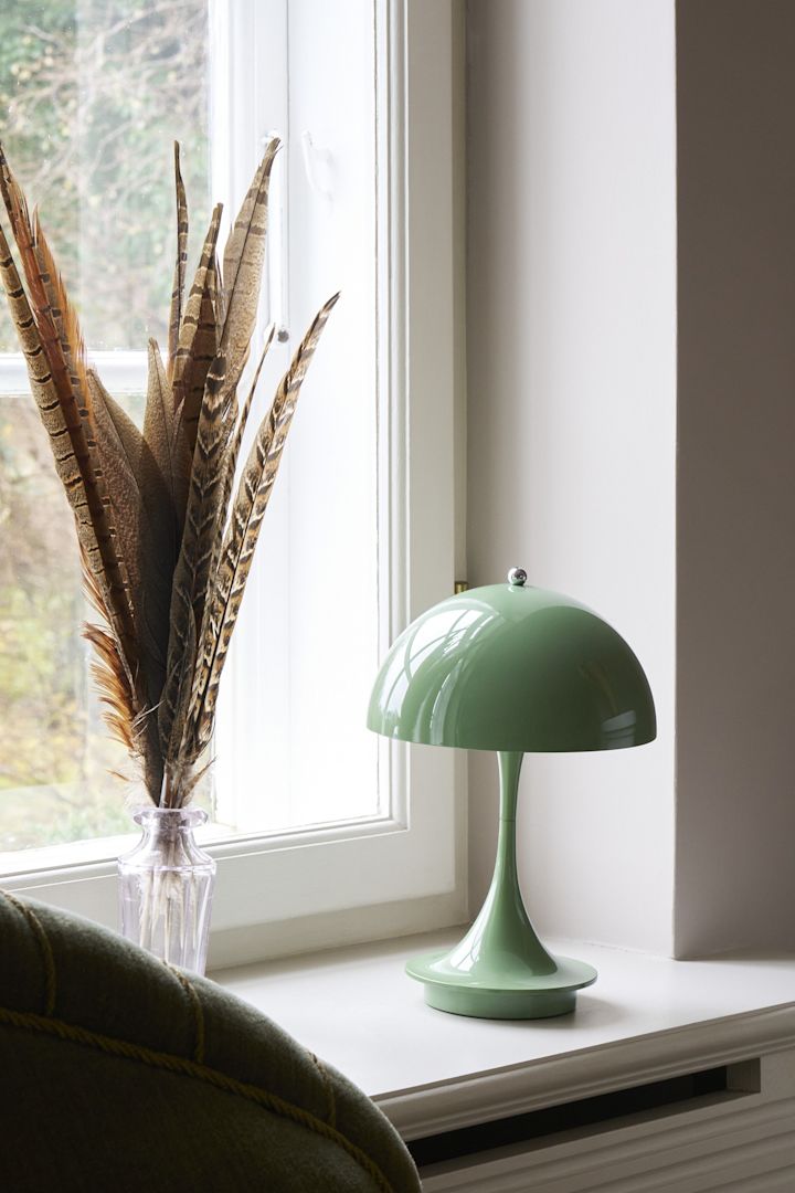 Die Farbe Salbei gehört zu den Einrichtungstrends des Herbstes 2025. Hier steht die salbeifarbene Panthella-Tischleuchte von Louis Poulsen auf einer Fensterbank.