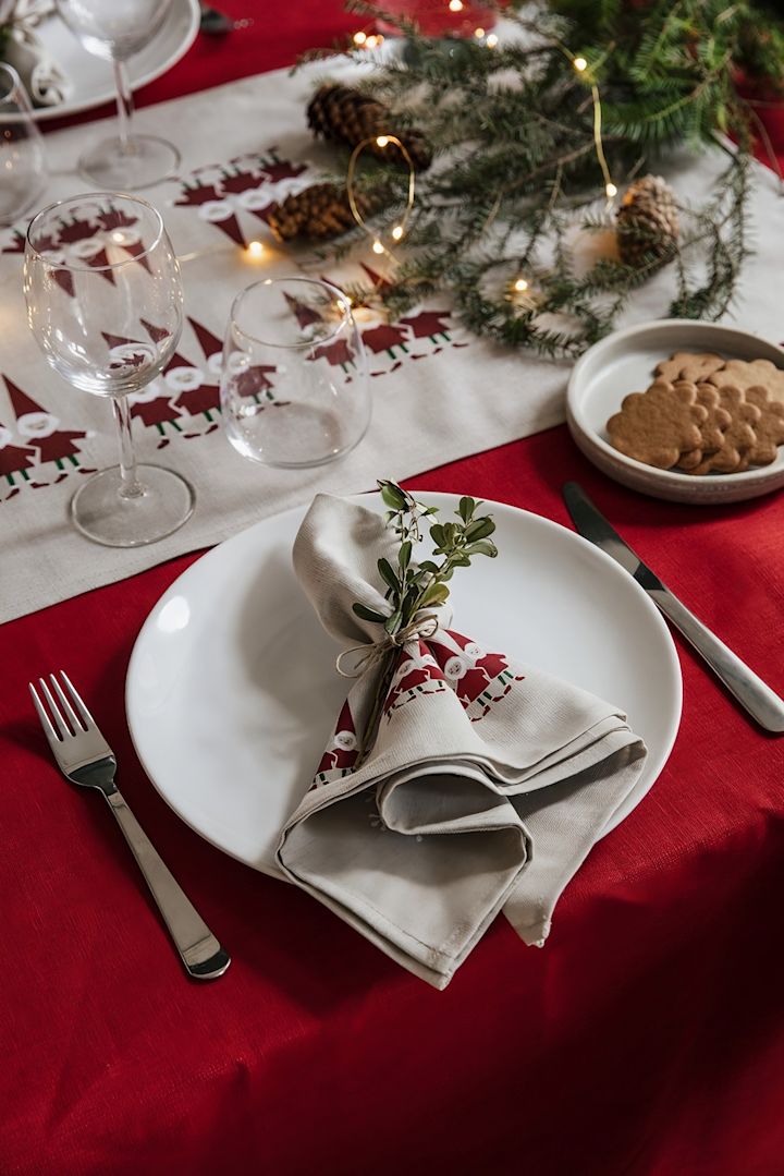 Zur perfekten skandinavischen Weihnachtsdeko gehören auch die passenden Textilien. Hier sehen Sie einen weihnachtlich gedeckten Tisch mit Tischdecke und Serviette aus der Tomtenisse-Kollektion von Almedahls.