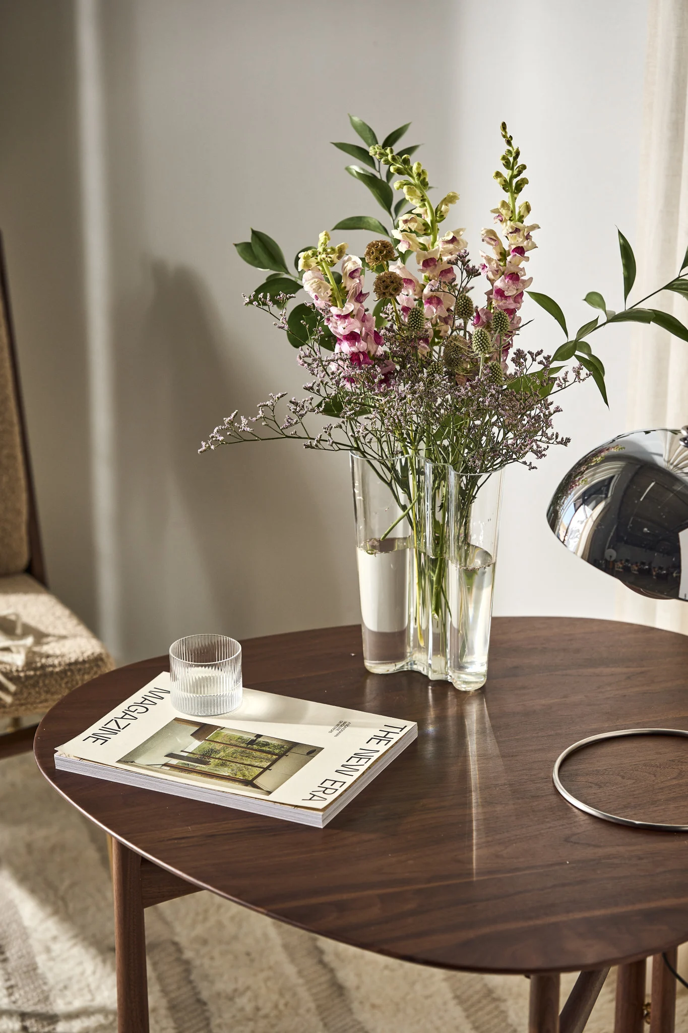 Auf einem Bestelltisch steht die hohe Alvar Aalto Vase Iittala mit frischen Blumen.